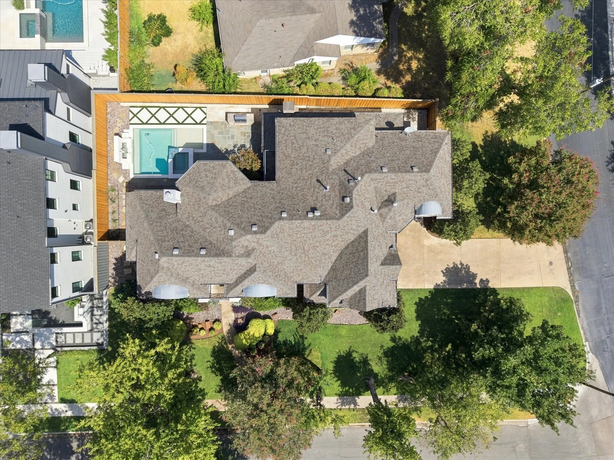 Expansive property featuring a multi-gabled roofline, front lawn, extended driveway, and a backyard with a swimming pool and patio