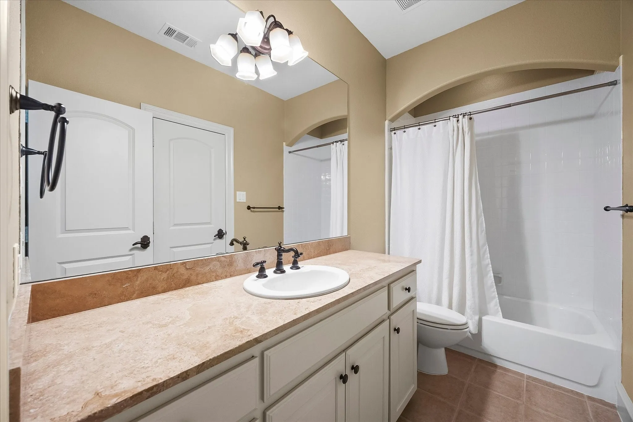 Bathroom featuring a single vanity with an integrated sink, broad wall mirror, and a combination shower/tub