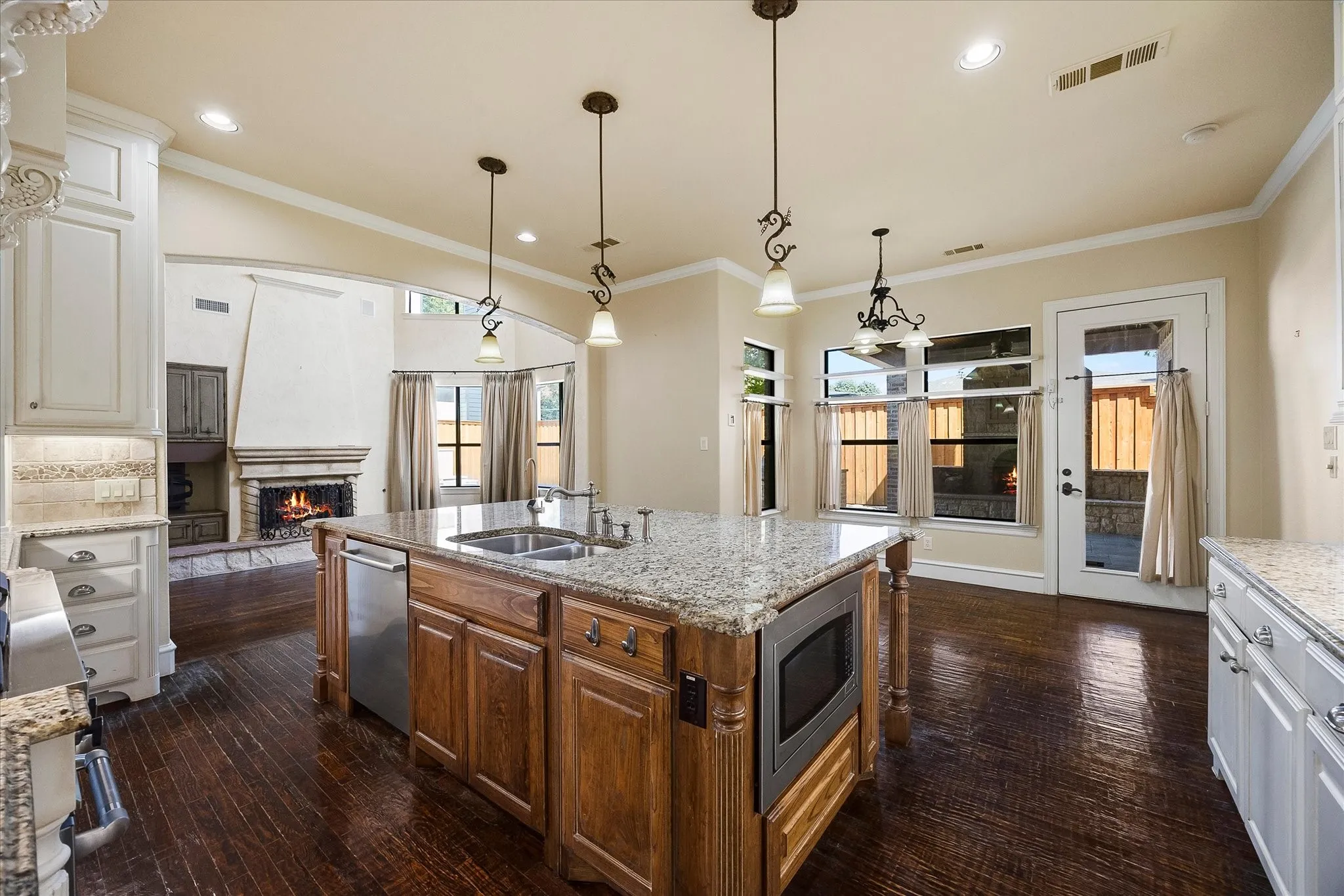 Kitchen featuring a large central island with a built-in microwave, wood-finish flooring, granite countertops, and recessed lighting