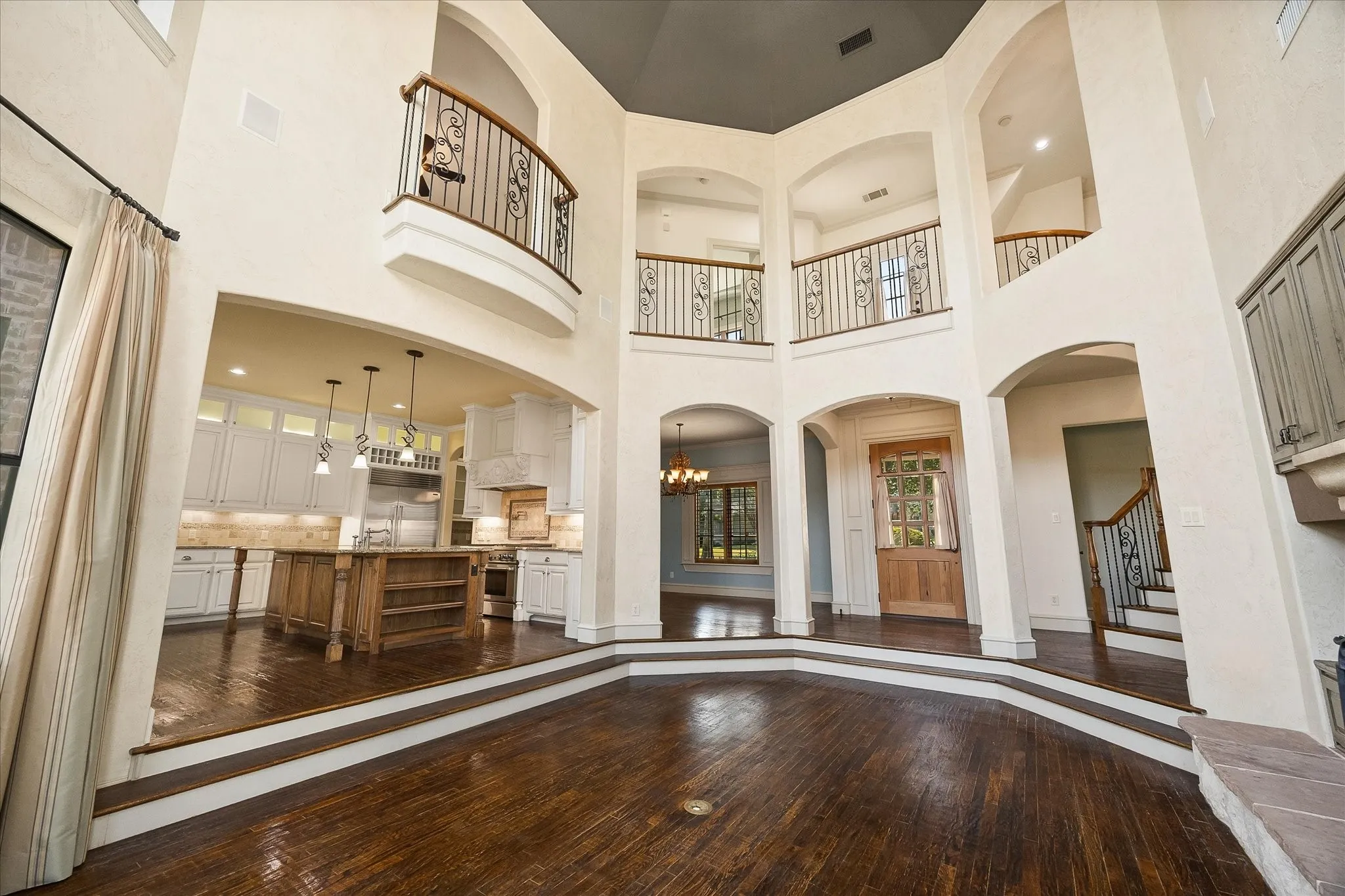 Grand foyer featuring dark wood-finish flooring and a multi-story ceiling