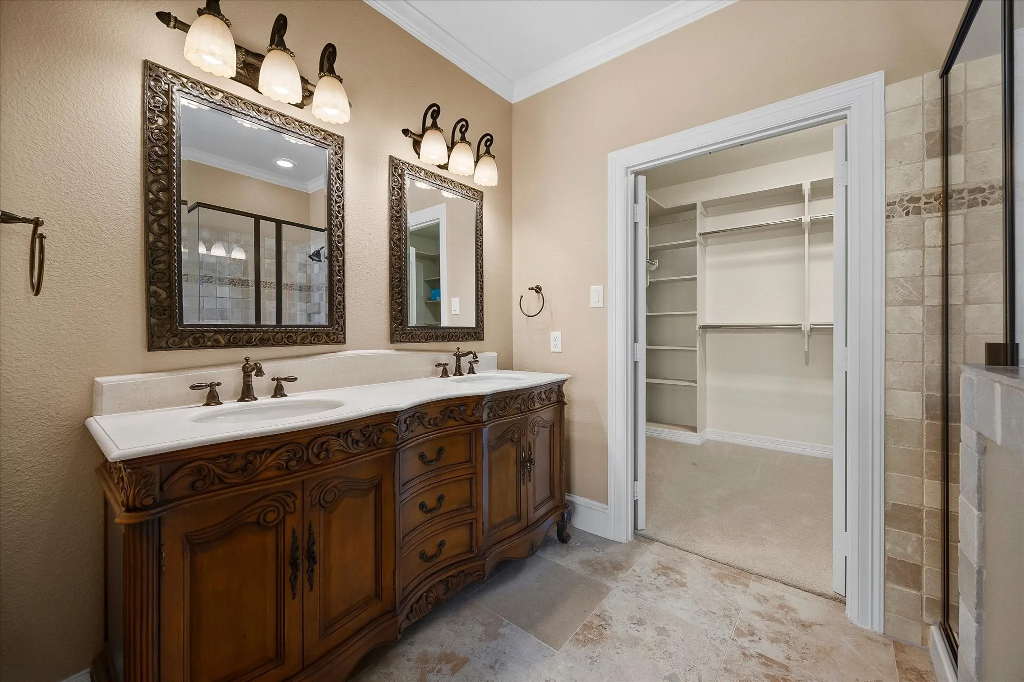 Dual vanity with carved wood cabinetry and white countertops, individual framed mirrors, and overhead light fixtures