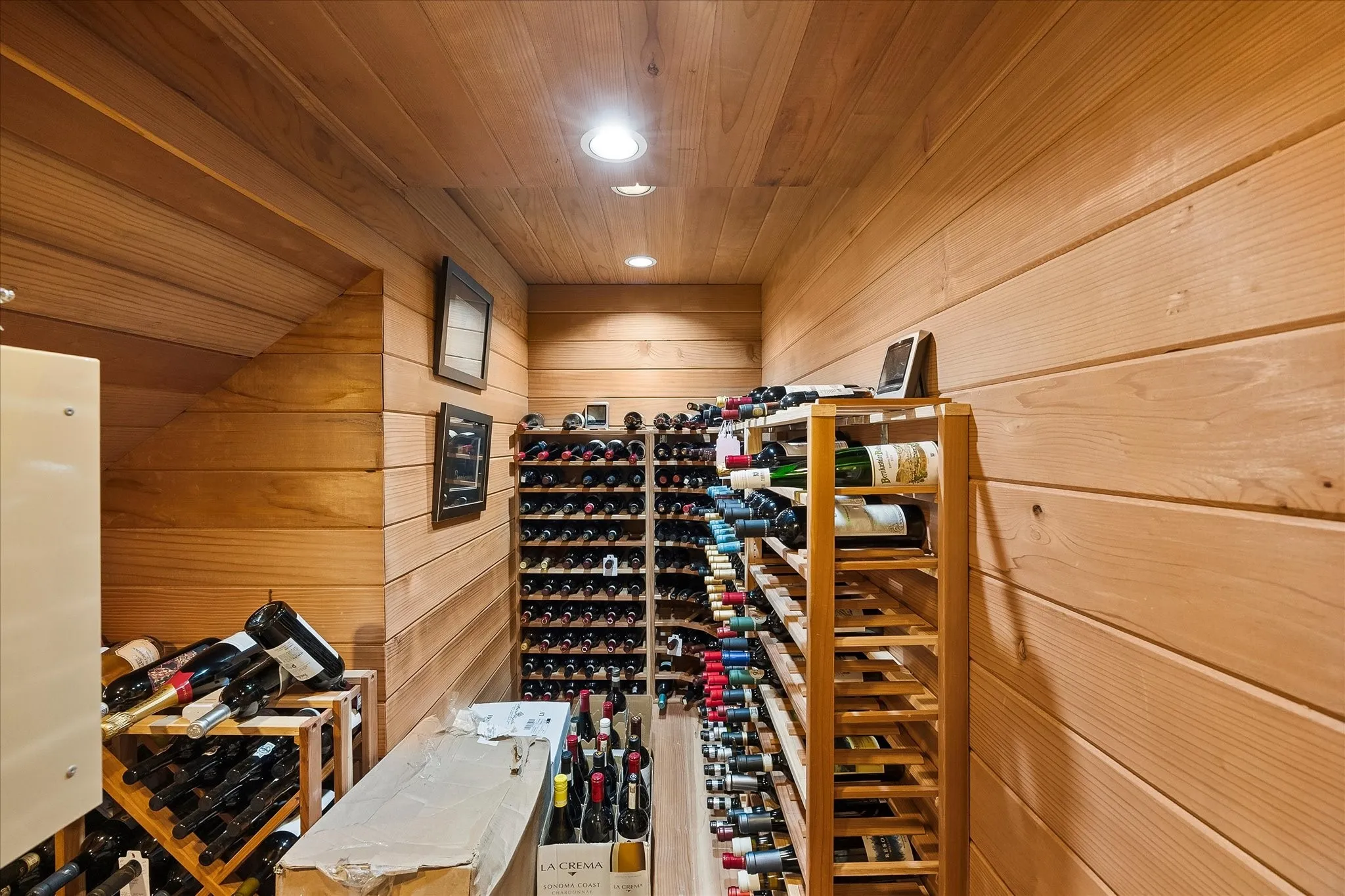 Wood-paneled walls and ceiling, built-in recessed lighting, and dedicated wine storage racks