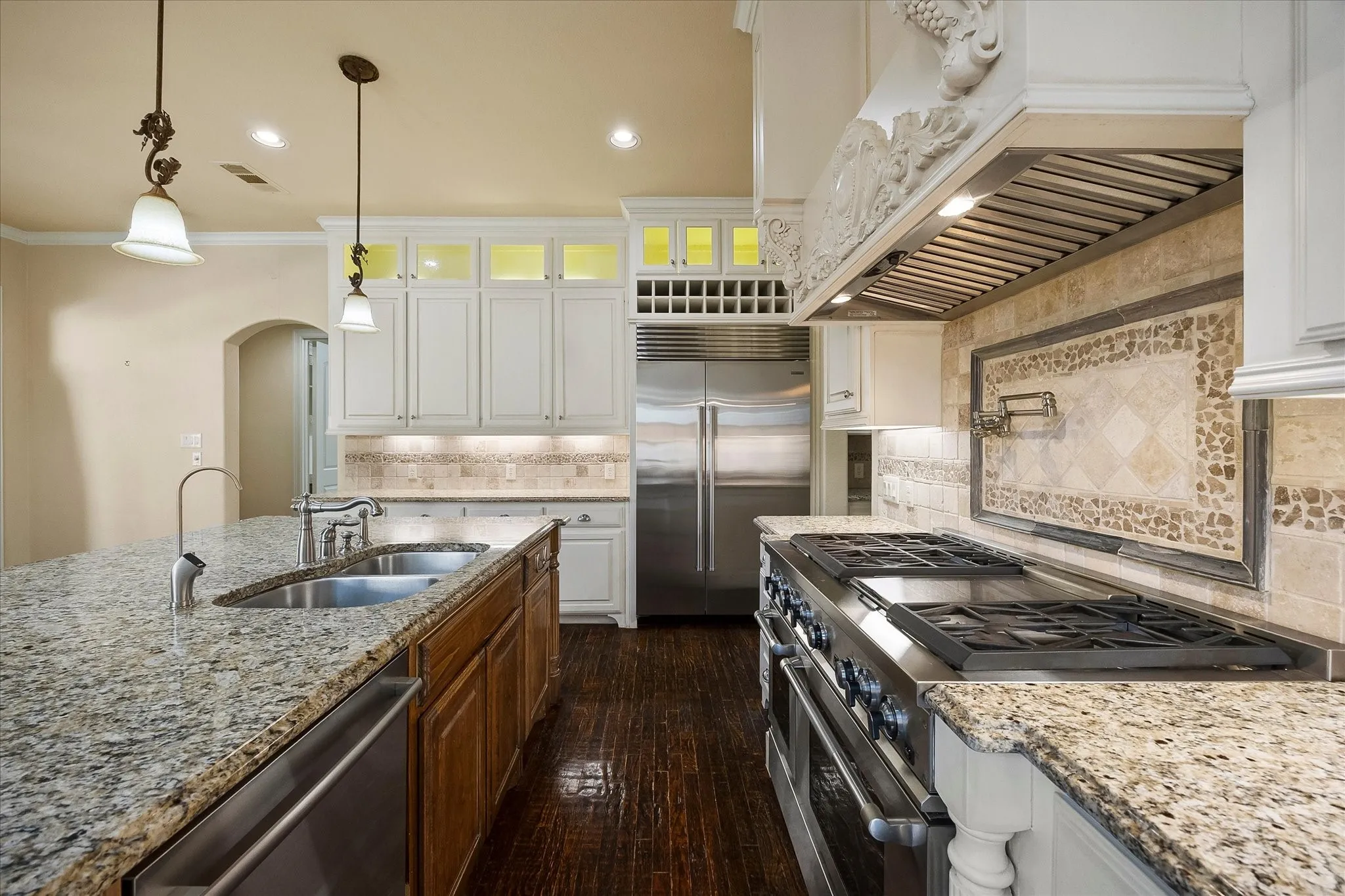 Gourmet kitchen featuring granite countertops, stainless steel appliances, white cabinetry, and wood-finish flooring