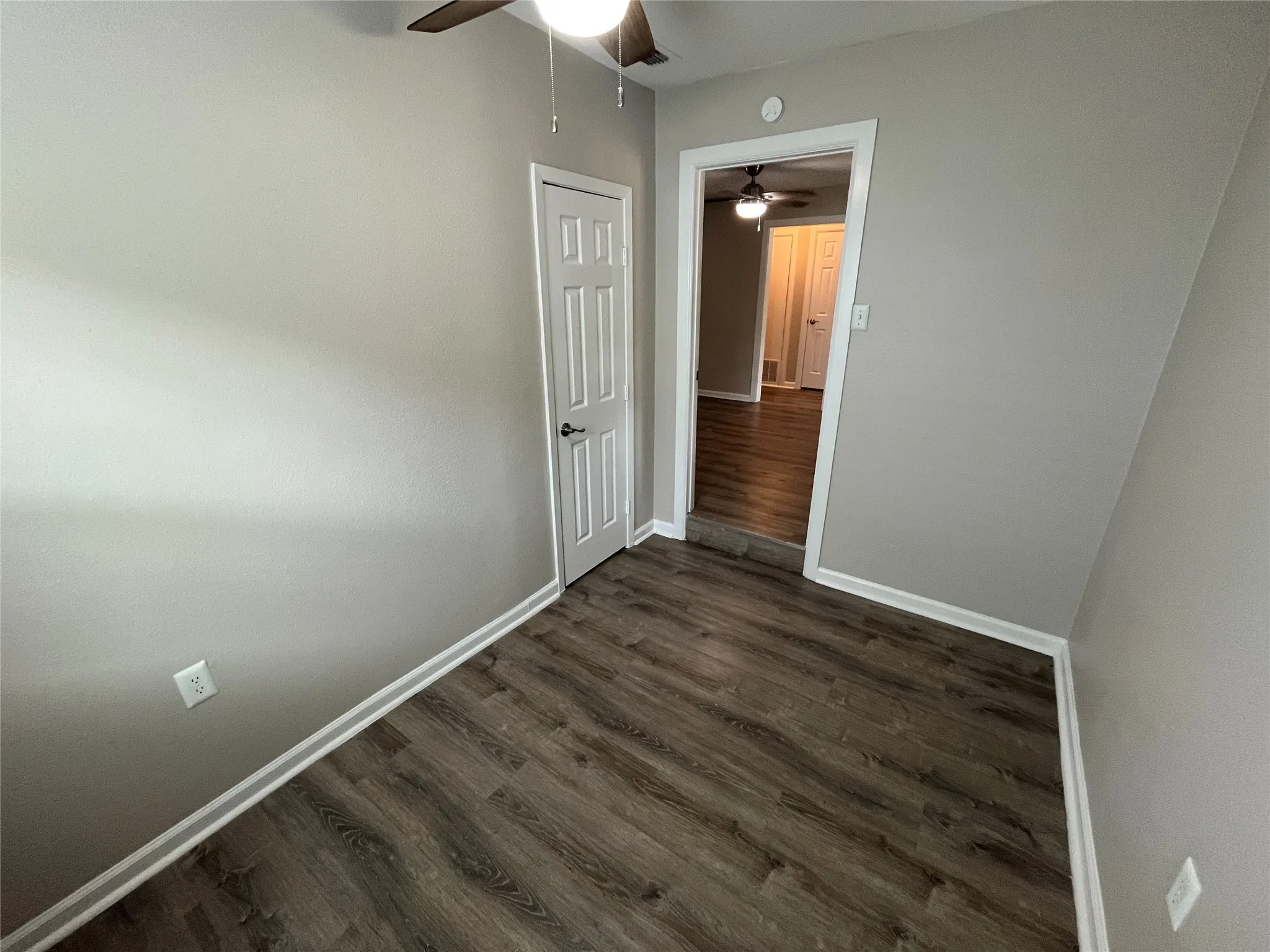 Wood-finish flooring, light gray wall finishes, white trim, and a ceiling fan