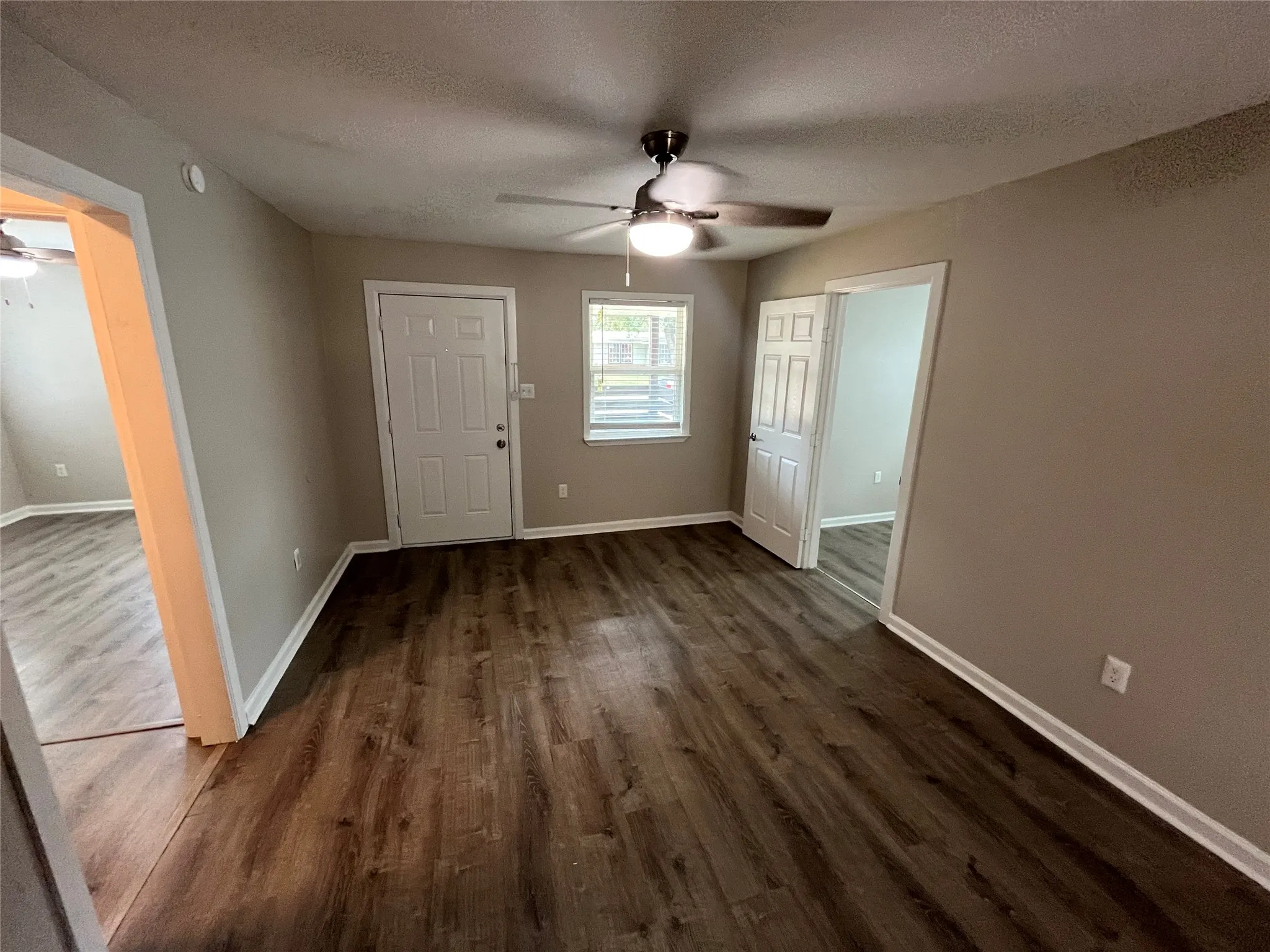 Wood-finish flooring throughout, neutral painted walls, and a modern ceiling fan with integrated lighting