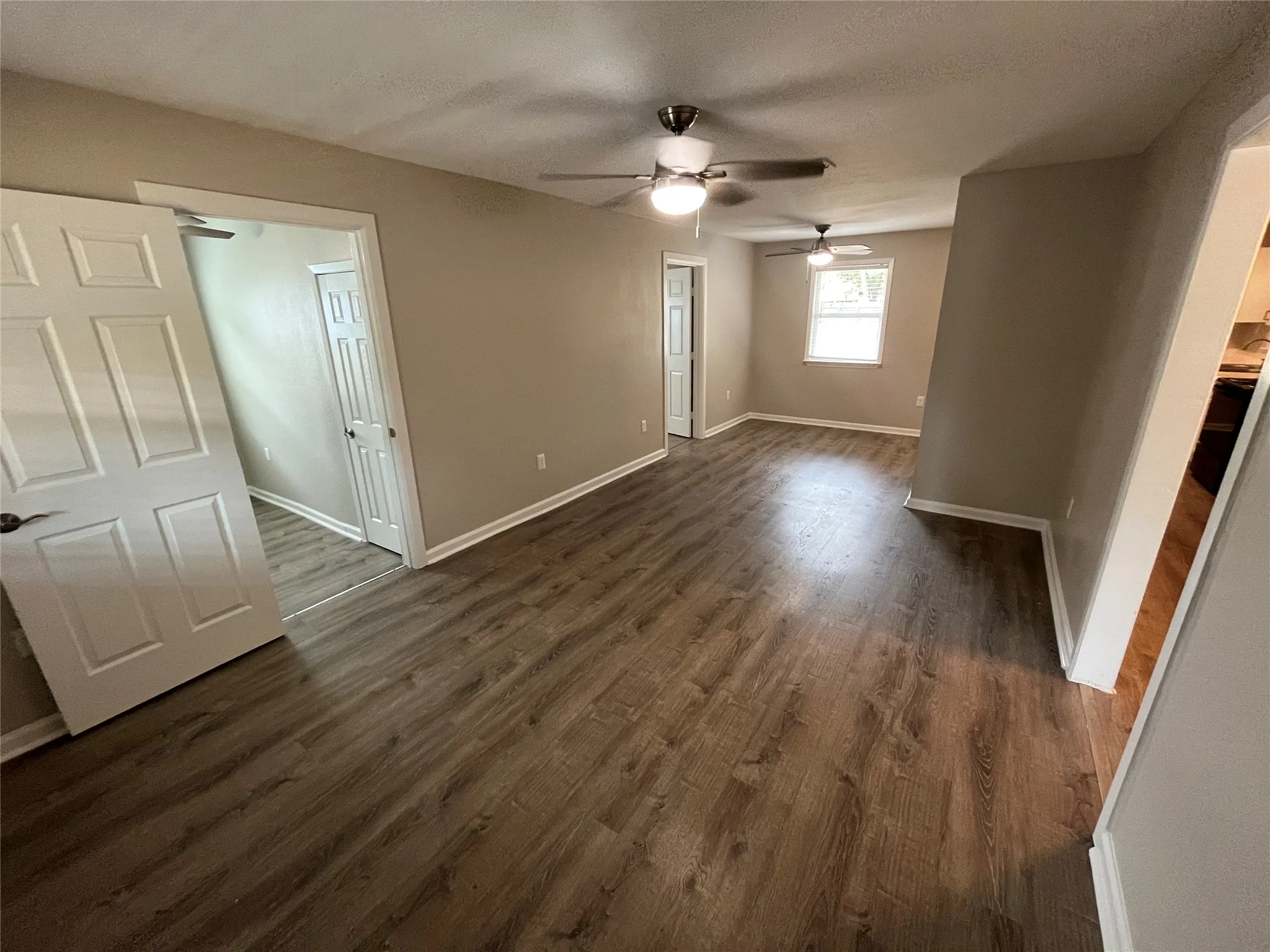 Wood-finish flooring, neutral wall paint, white trim, and two ceiling fans