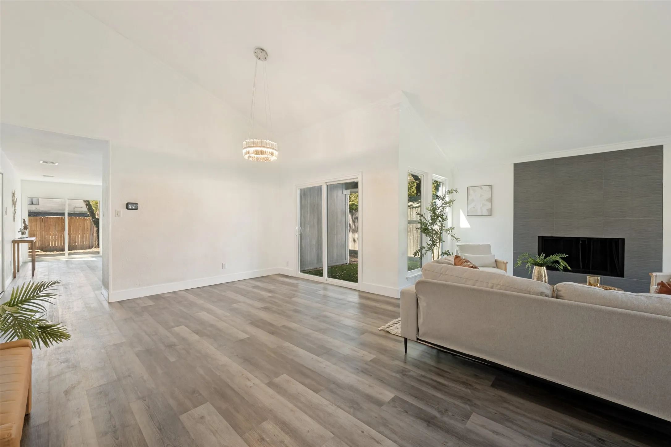 Vaulted ceiling with an attached chandelier, wood-finish flooring, and a fireplace with a dark tile surround