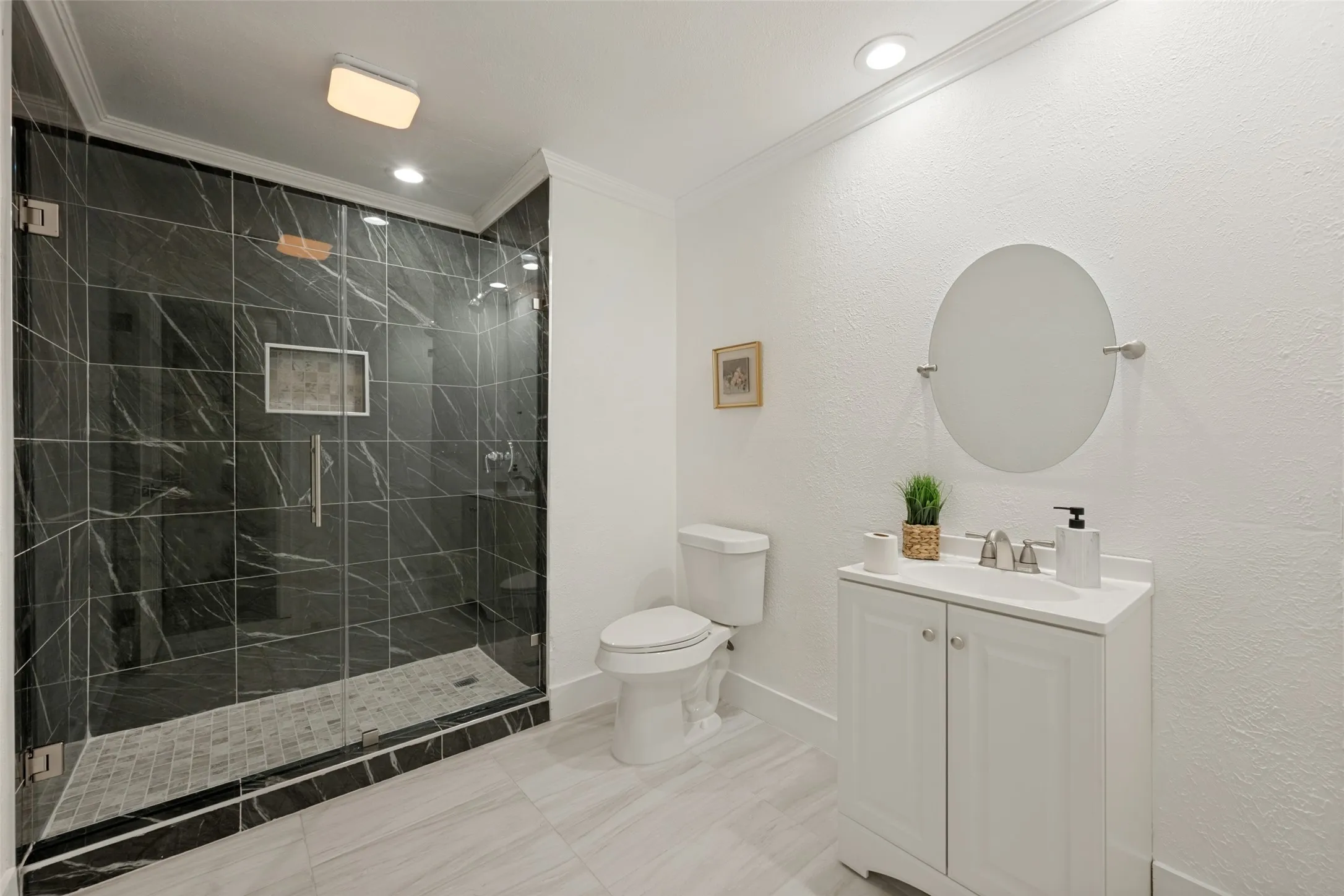 Glass-enclosed shower with dark tile surround, integrated shower niche, and mosaic tile​​‌​​​​‌​​‌‌​‌‌​​​‌‌​‌​‌​‌​​​‌​​ pan