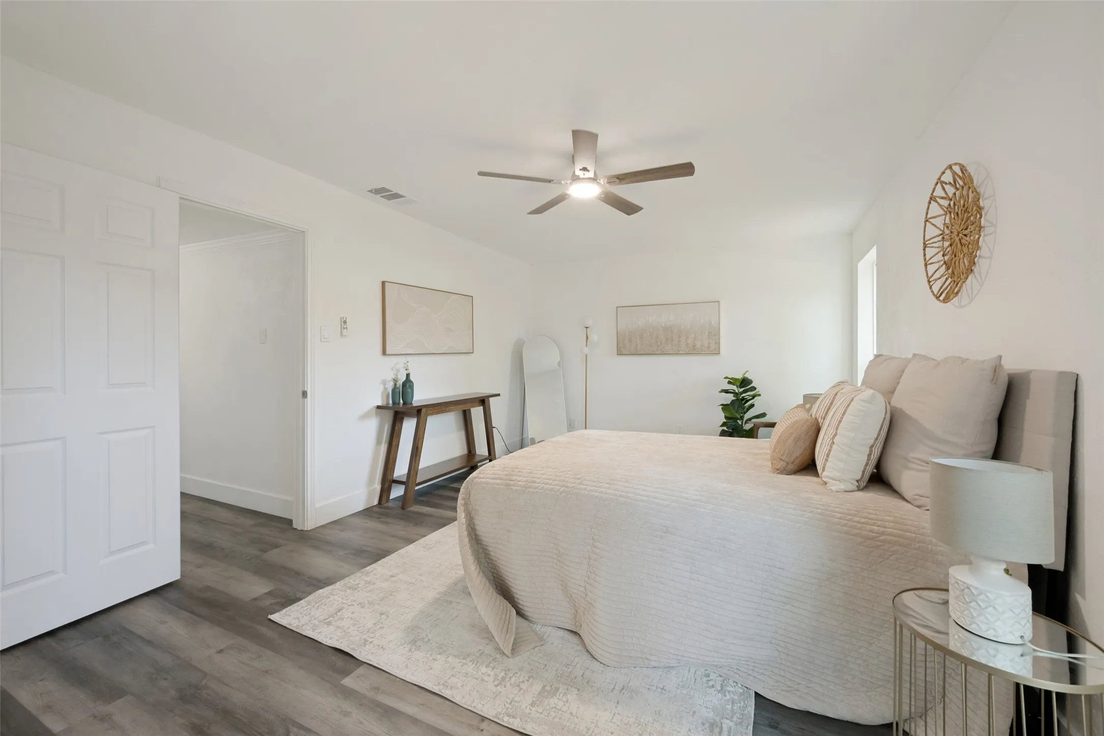 Wood-finish flooring, white walls, and a ceiling fan with integrated lighting