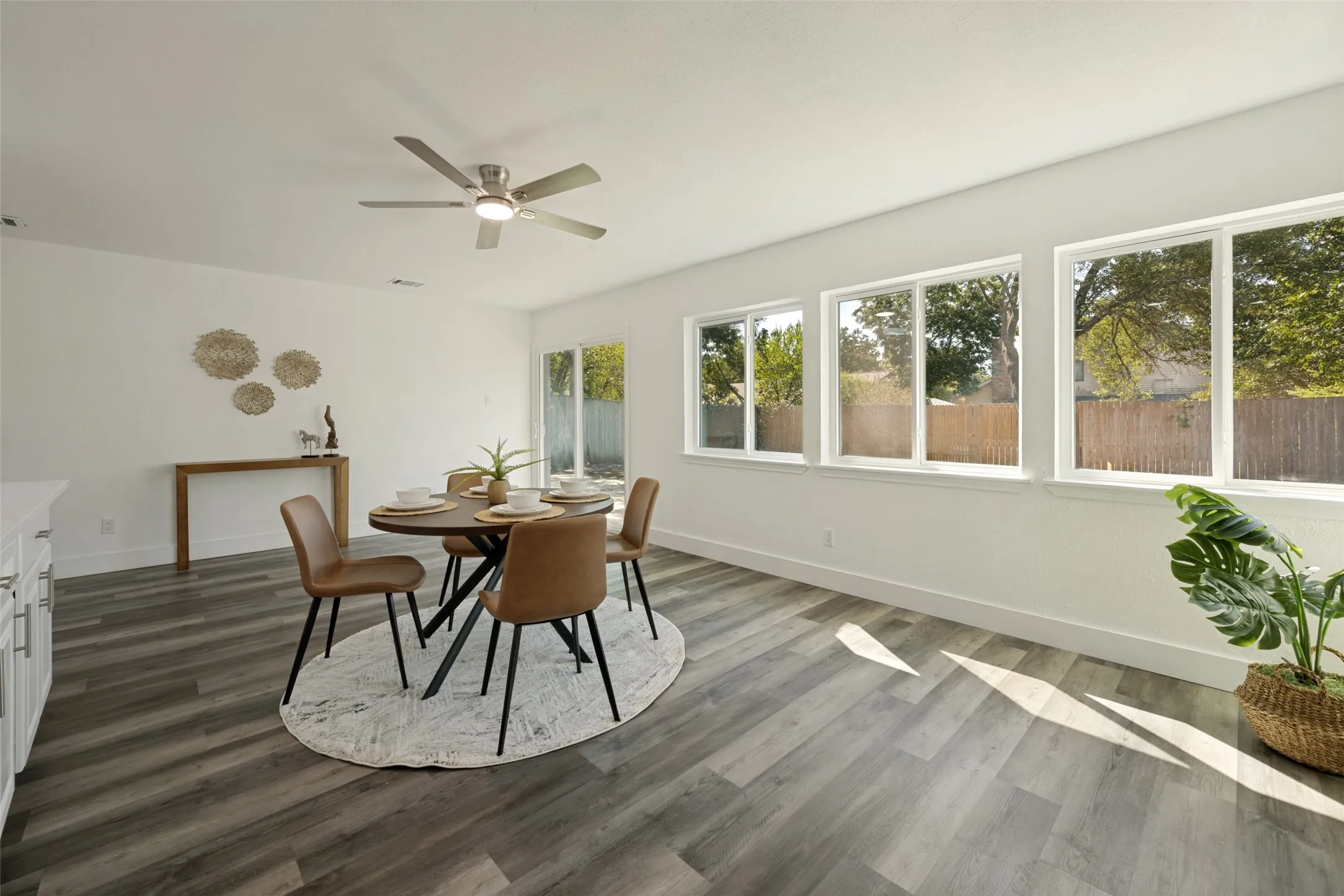 Bright interior with wood-finish flooring, a ceiling fan, and multiple windows