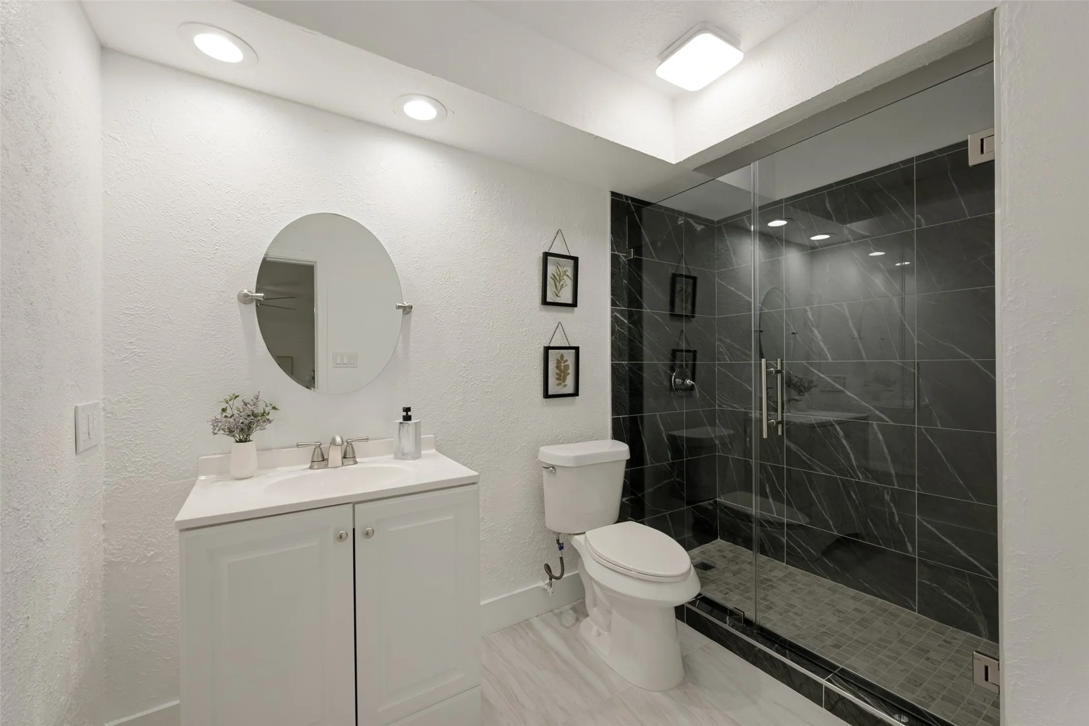 White vanity with a single basin sink, brushed nickel faucet, and a circular mirror