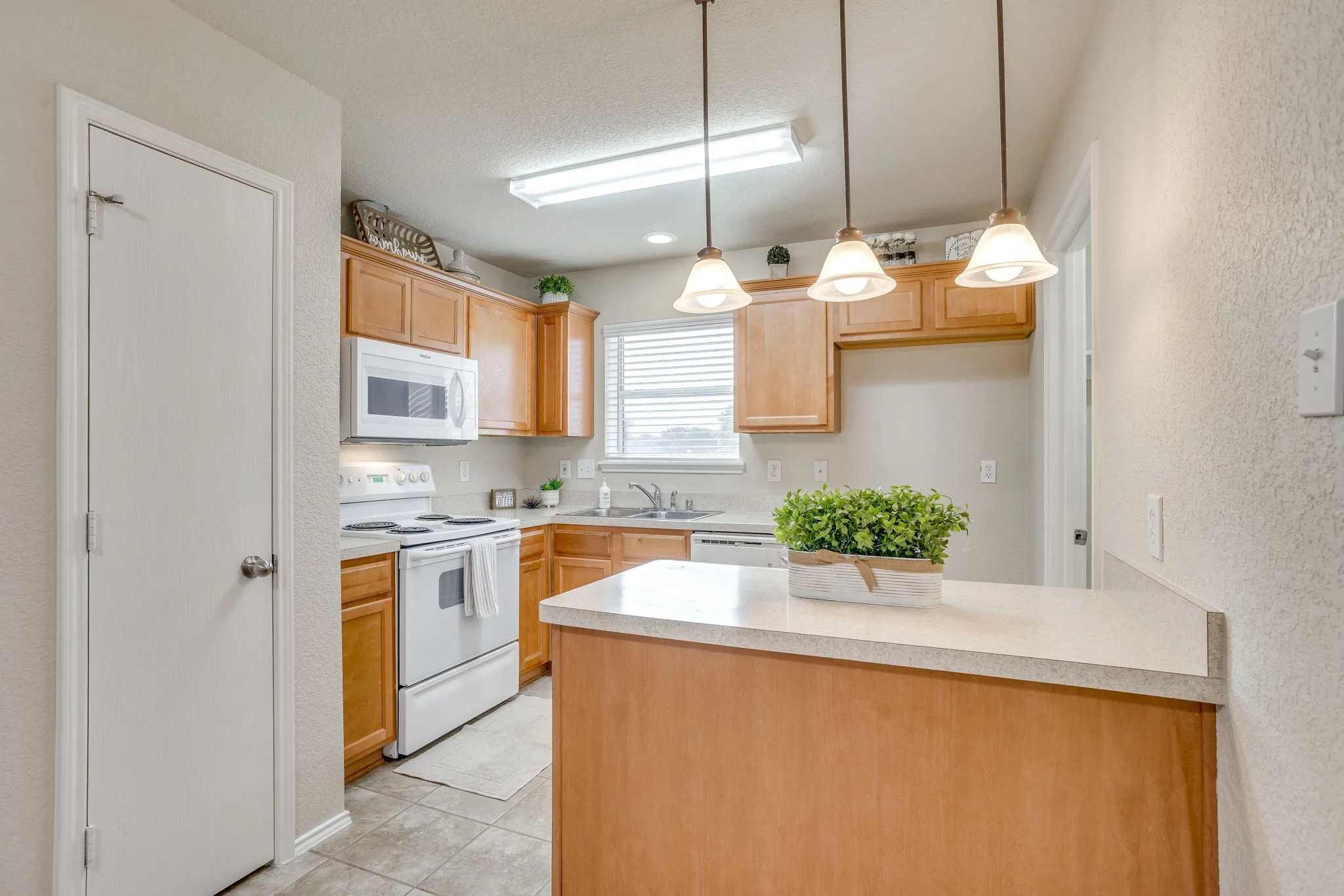 Kitchen featuring wood-finish cabinetry, white appliances, a breakfast bar, and tile flooring