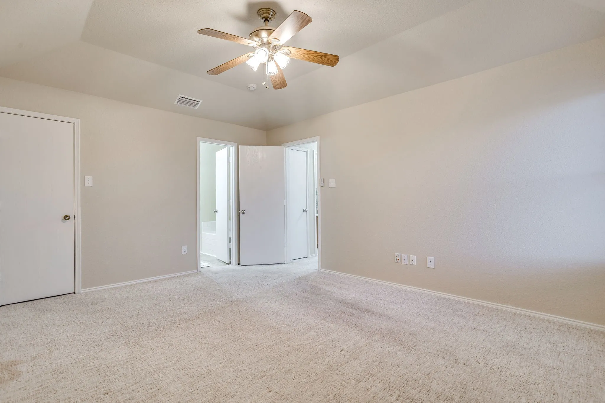 Neutral-toned carpeting, tray ceiling, and a ceiling fan with integrated lighting
