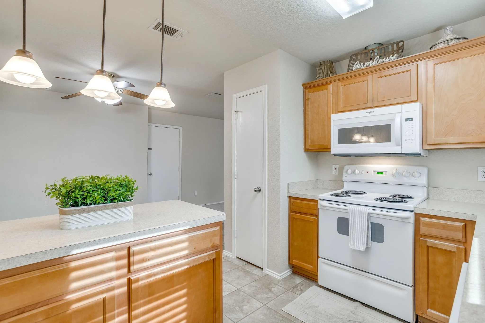 Light wood-finish cabinetry, white countertop, white range, and white microwave