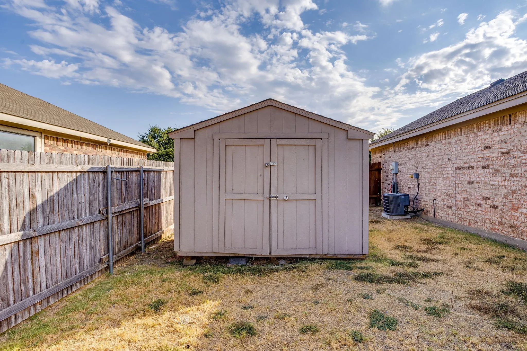 Exterior storage shed with double doors, pitched roof, and wood-panel siding