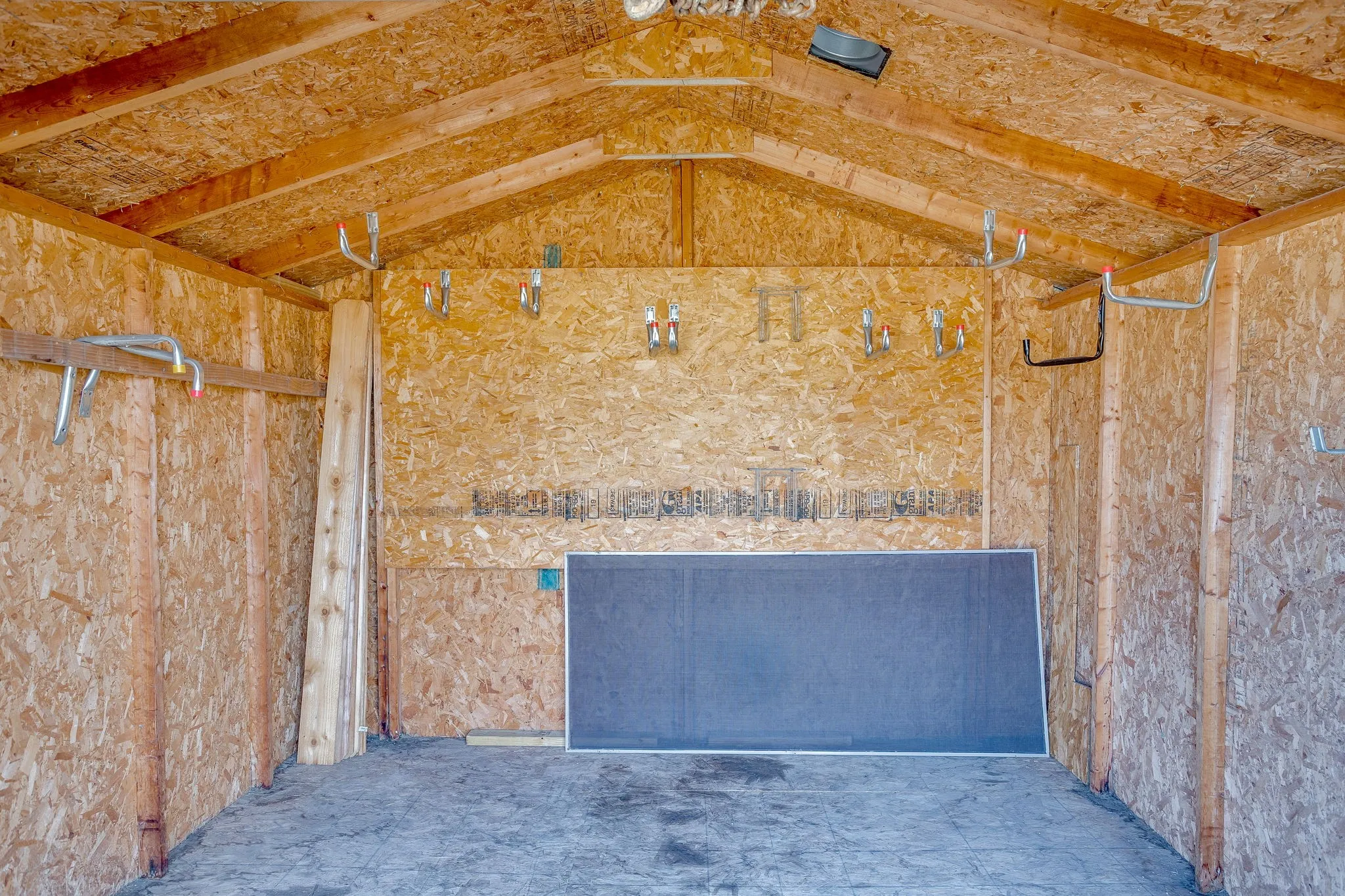 Exposed wood beam ceiling with oriented strand board walls and concrete flooring