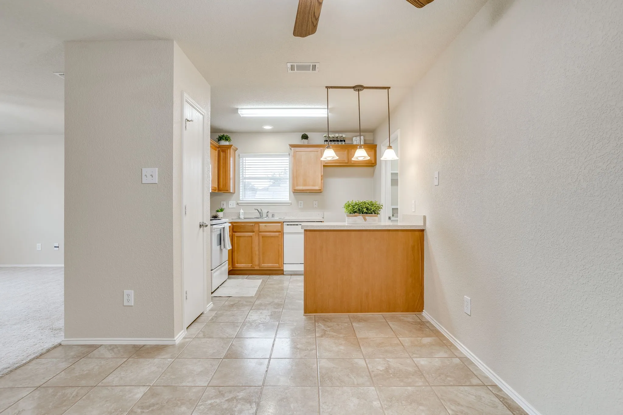 Kitchen featuring wood cabinetry, white appliances, a breakfast bar, and tile flooring
