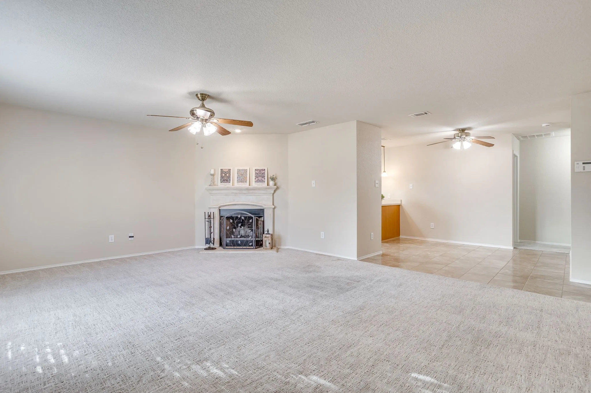 Expansive living space with a fireplace, ceiling fan, and carpeted flooring