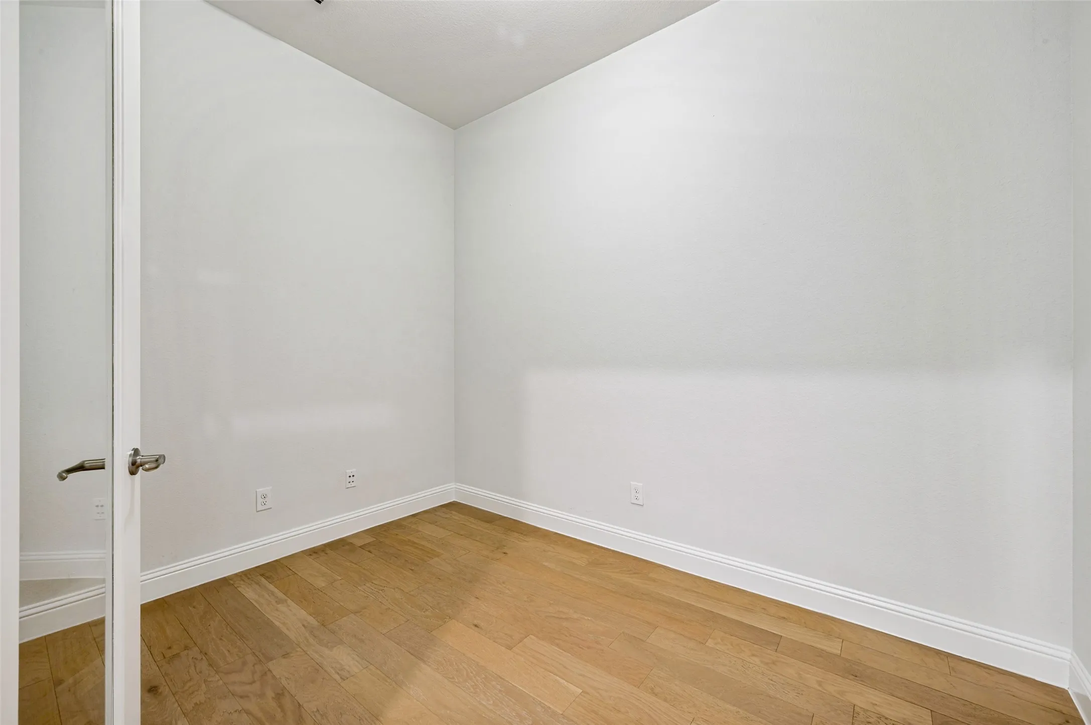 Private home office featuring beautiful hardwood floors and elegant glass French doors. Tucked just off the entry, this dedicated workspace offers a quiet, versatile setting for working from home while maintaining an open and sophisticated feel.