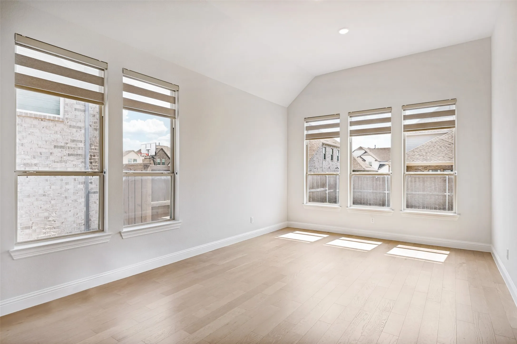 Bright and inviting dining area surrounded by an abundance of windows that fill the space with natural light. Soaring ceilings, beautiful hardwood floors, and decorative window shades create an airy, elegant setting perfect for both casual meals and entertaining.