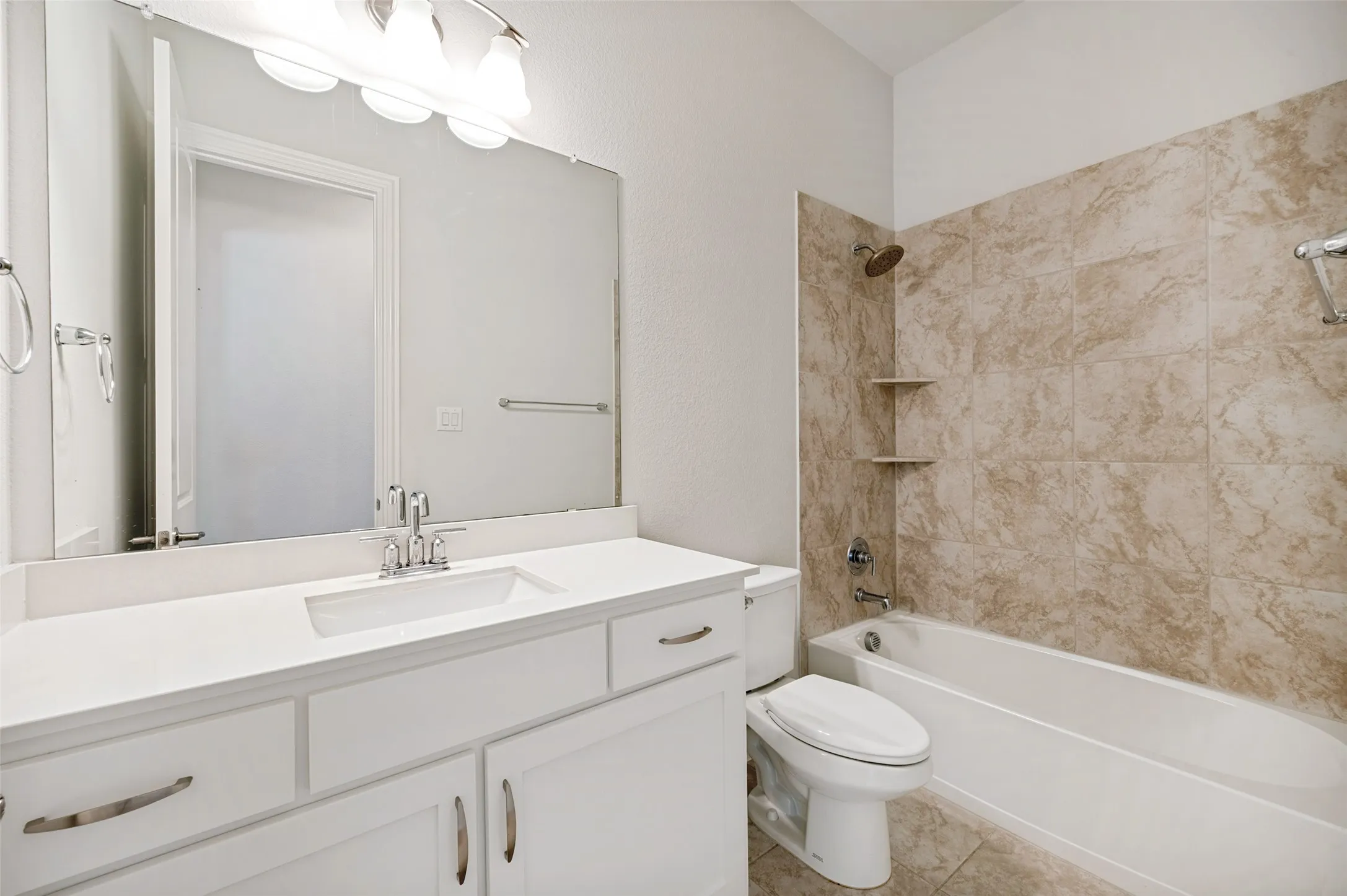 Well-appointed secondary bathroom conveniently shared by the two additional bedrooms, featuring a spacious vanity with ample cabinetry, a tub-and-shower combination with tile surround, and bright, neutral finishes for a clean and timeless look.