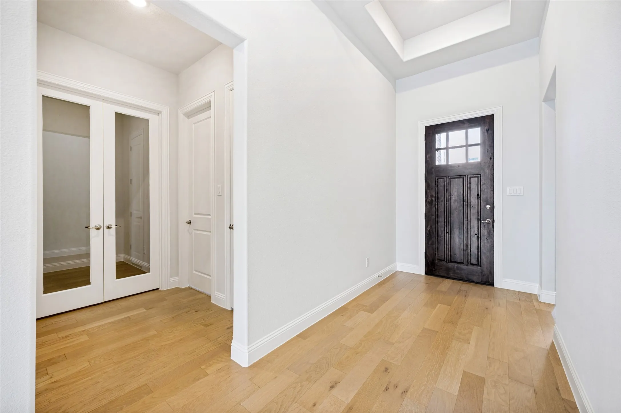 A welcoming entryway showcases beautiful hardwood floors, soaring ceilings, and a rich wood front door that adds warmth and character. Elegant glass French doors open to the private office, creating a sophisticated and inviting introduction to the home.