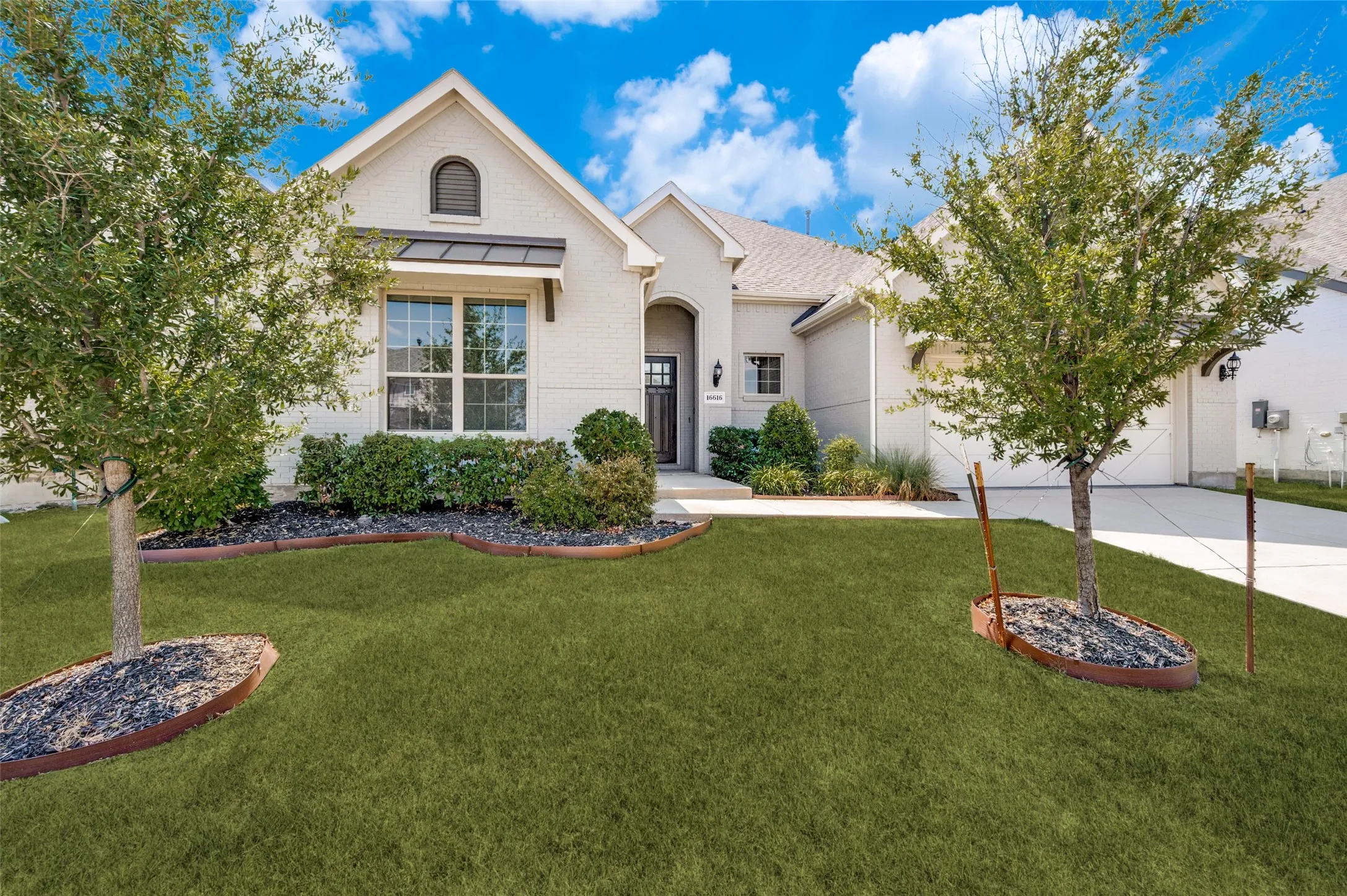 Beautiful curb appeal welcomes you home with timeless white brick, lush landscaping, and a charming covered entry that creates an elegant first impression.