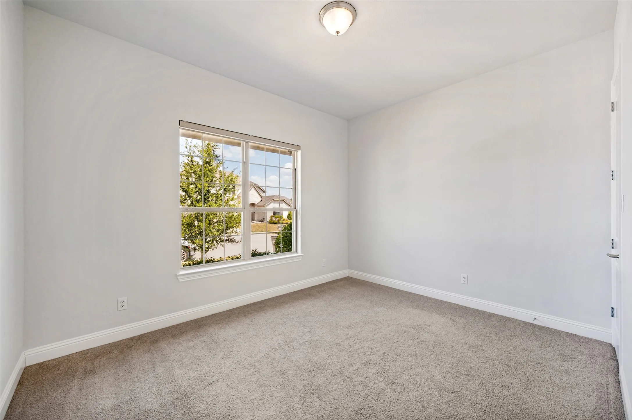 Bright and inviting secondary bedroom located at the front of the home, featuring plush carpeting, abundant natural light, and a spacious walk-in closet. The generous layout provides plenty of room for comfortable furnishings while offering excellent storage and privacy.