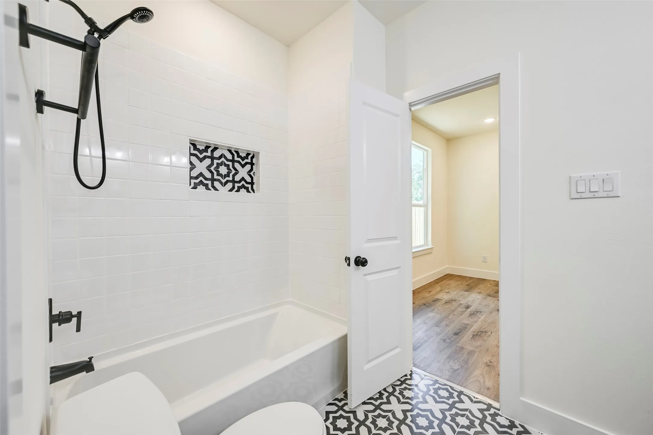 Bathroom featuring a white subway tile surround, patterned tile flooring, and matte black fixtures
