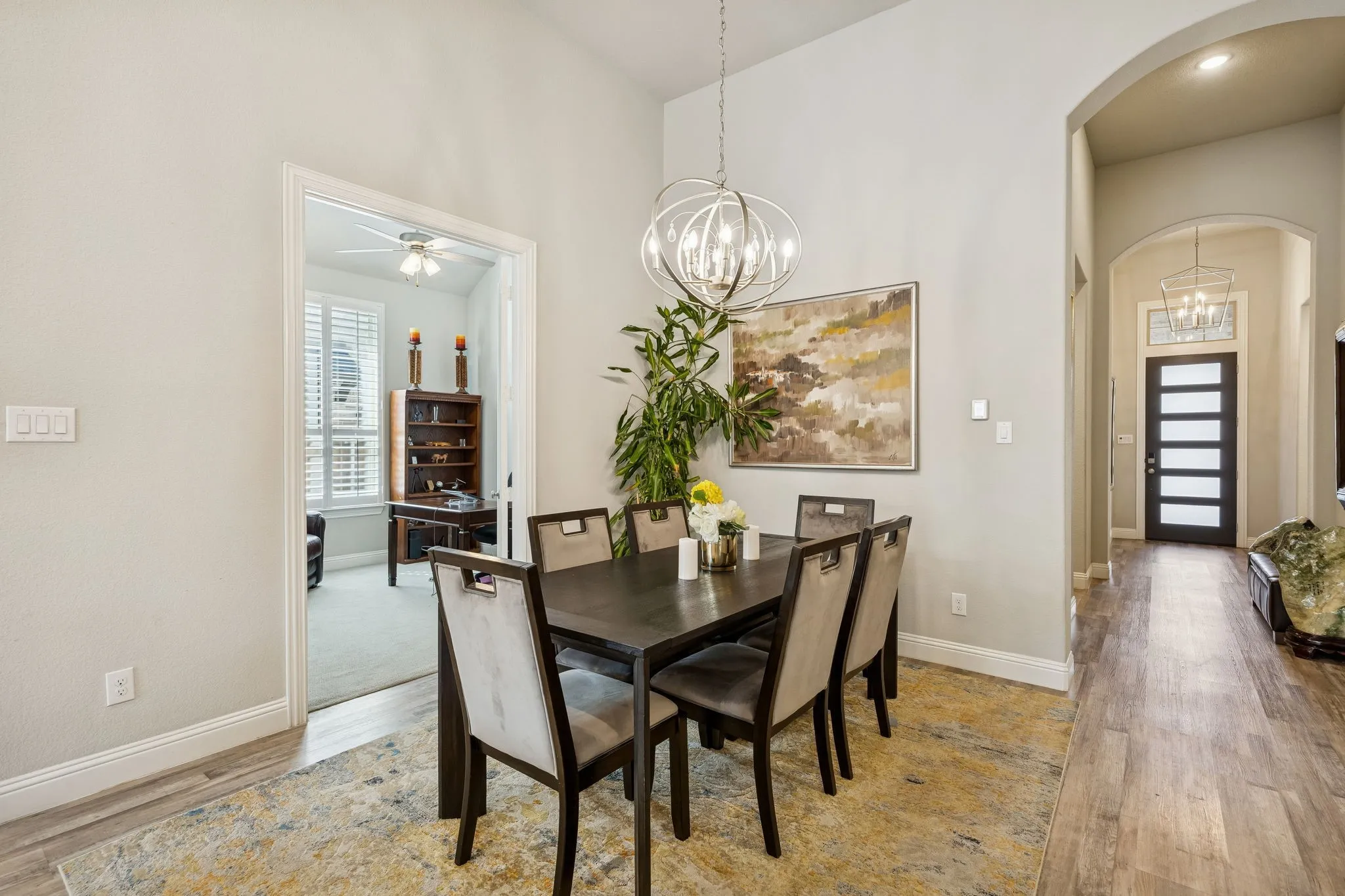 formal dining with high ceilings and modern light fixture with visibility of foyer by front door and office (optional bedroom) to the left.
