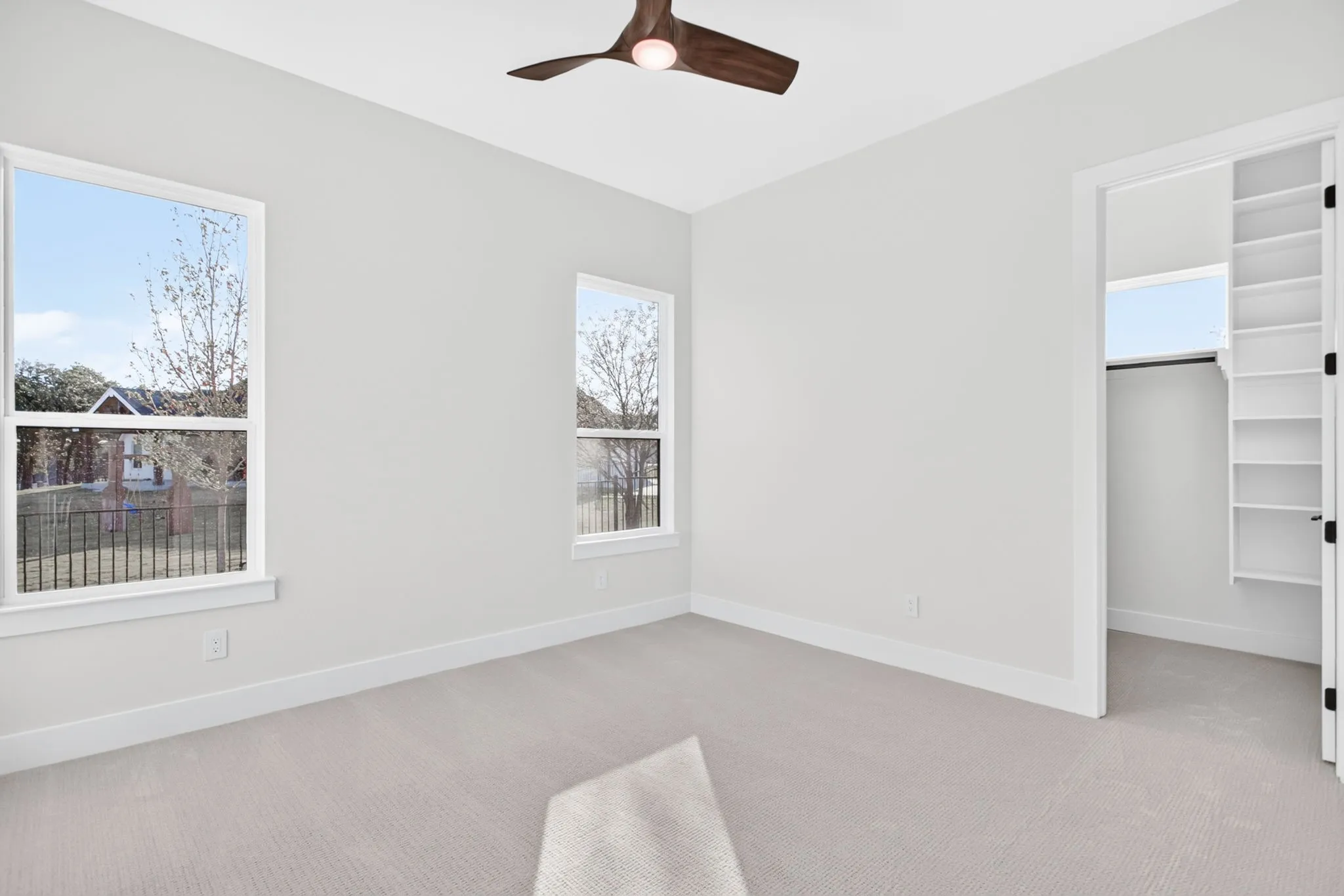 The bedroom on the other side with a glimpse of the really good-sized closets and handsome ceiling fans.