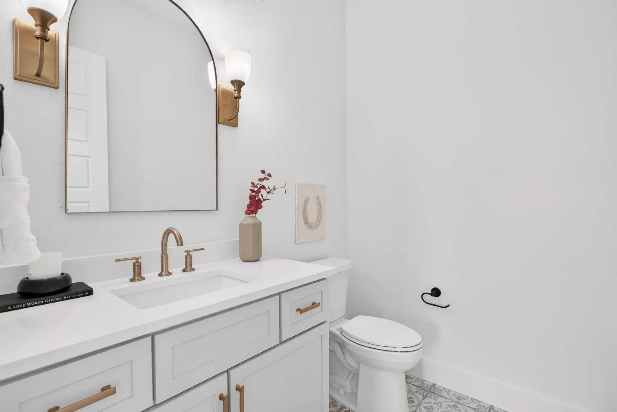 Powder bath with great storage, sconce lighting, custom mirror and tile flooring.