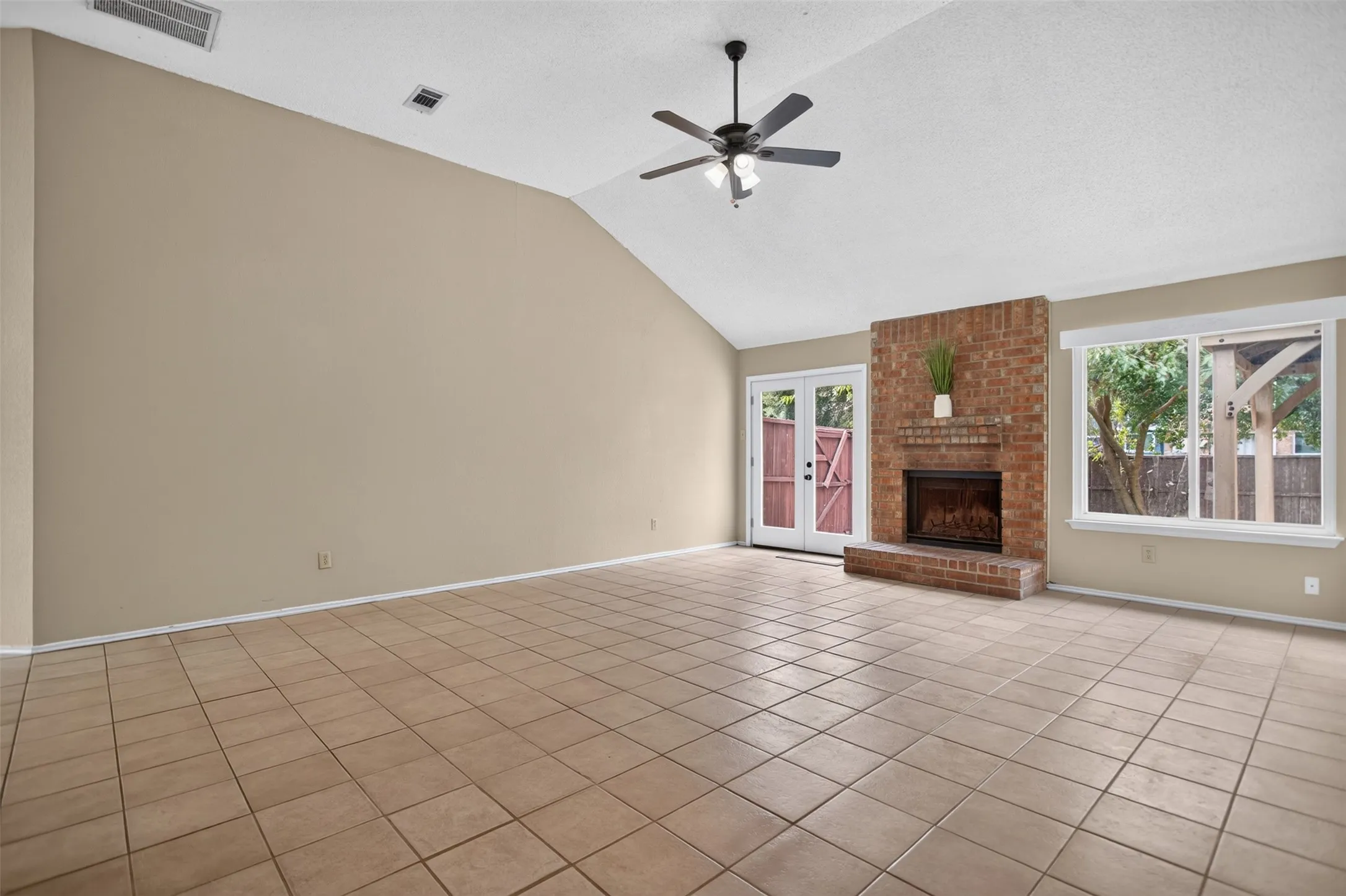 Living room with french doors to the back yard and brick fireplace.