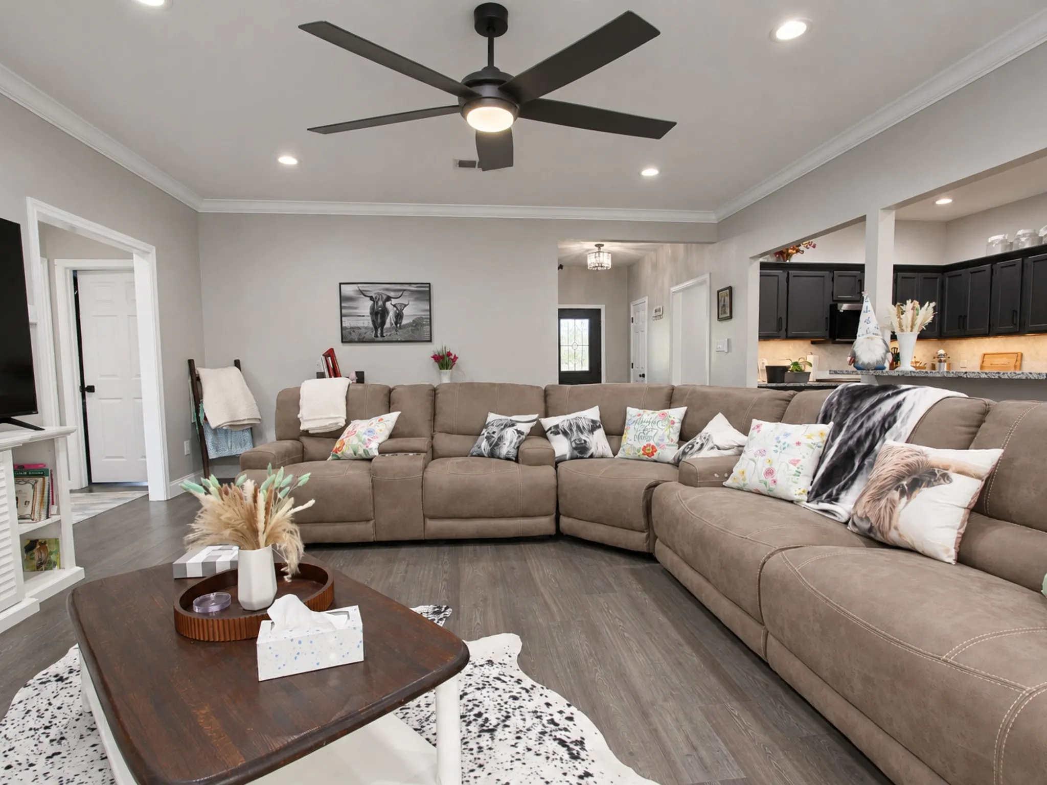 Open-concept living area featuring wood-finish flooring, a contemporary ceiling fan, recessed lighting, and crown molding