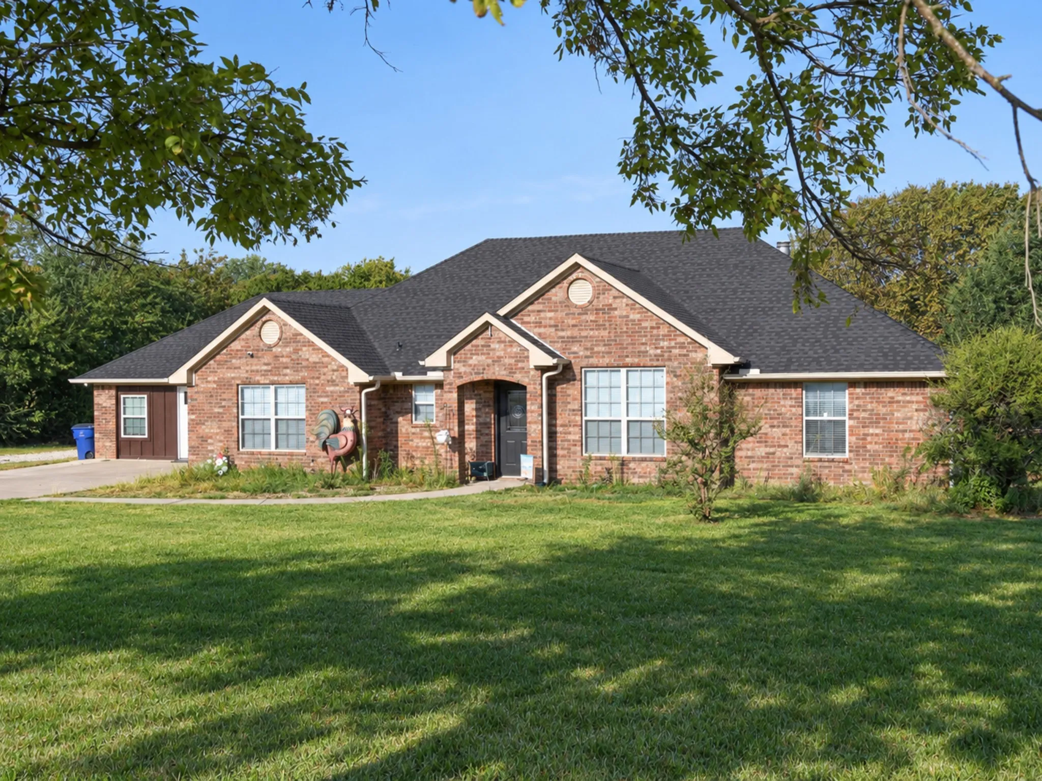 Brick exterior with a dark shingle roof, multiple windows, and a front-facing garage