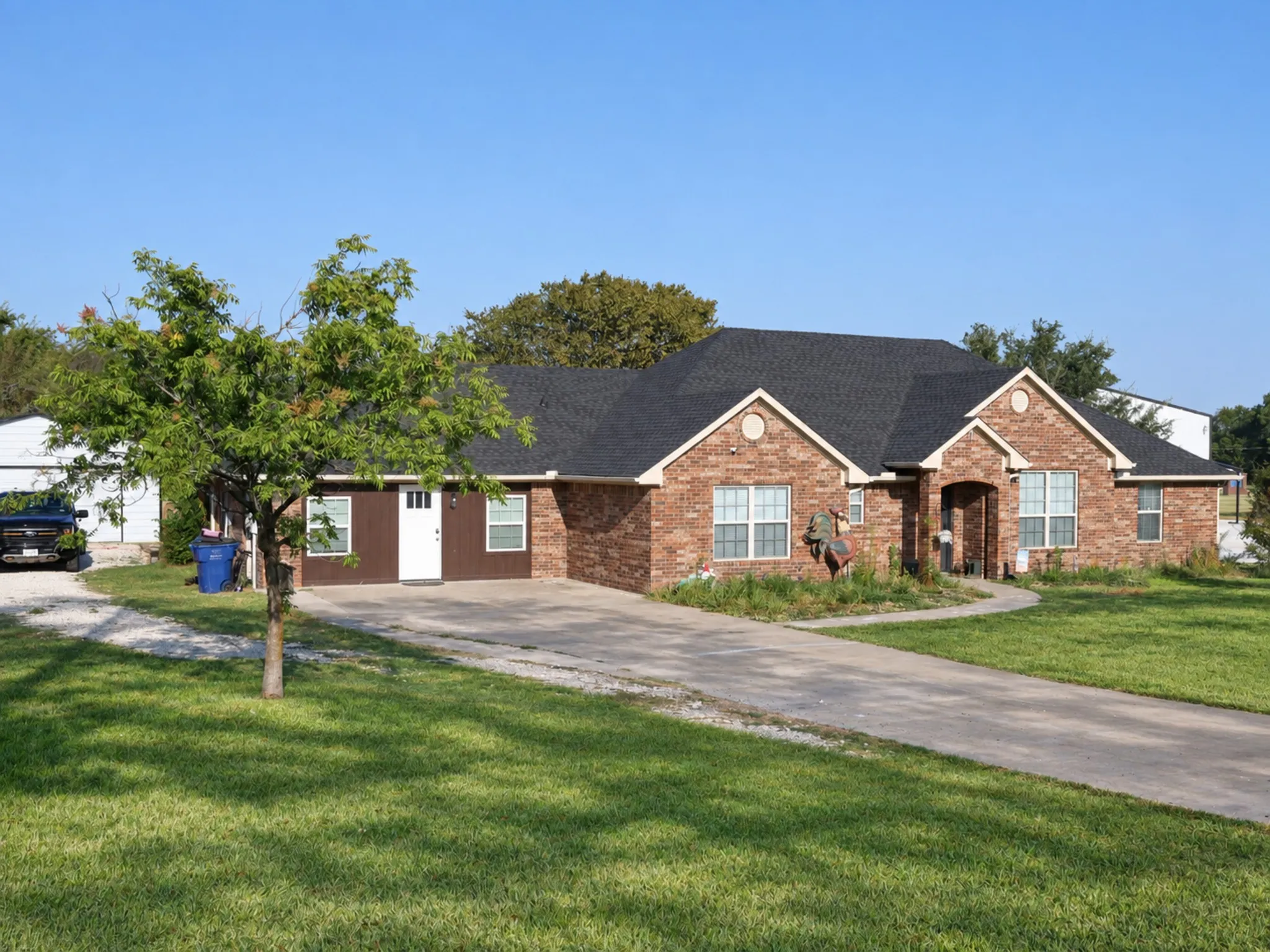 Brick exterior with a dark shingle roof and a mature tree