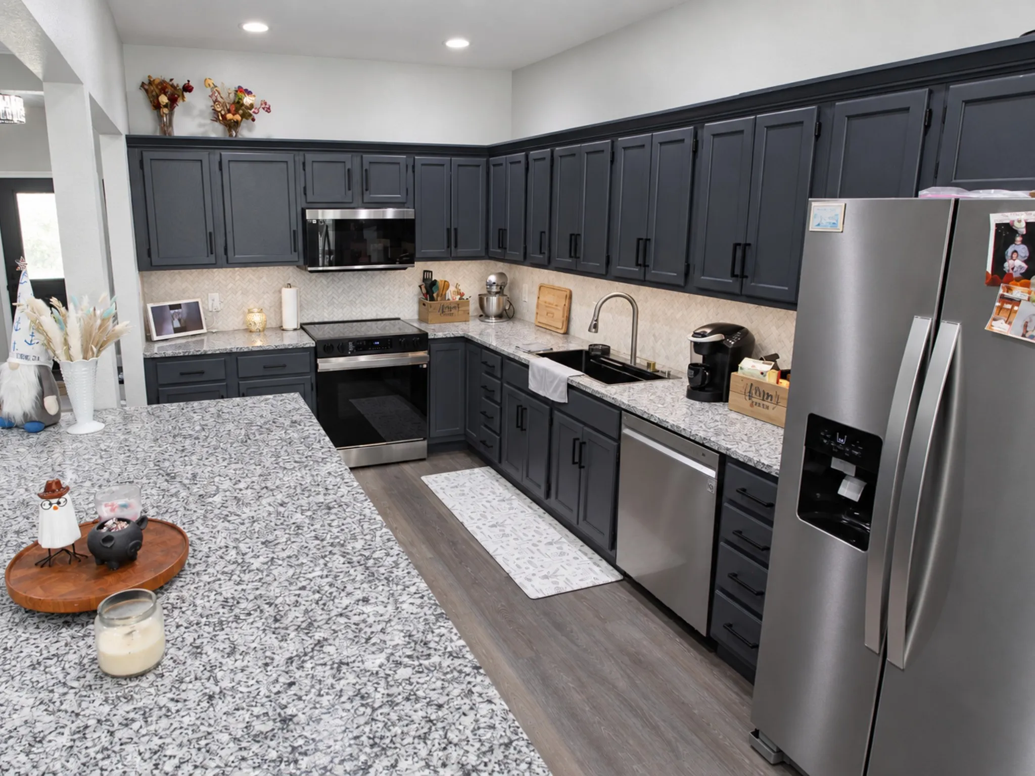 Granite countertops, dark wood-finish cabinetry, stainless steel appliances, recessed lighting, and wood-finish flooring