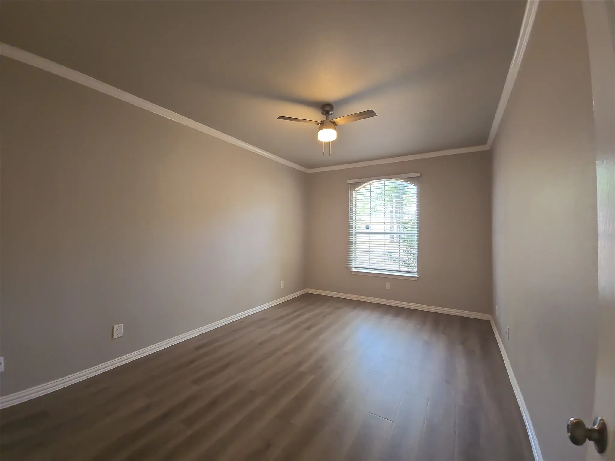Neutral wall paint, wood-finish flooring, ceiling fan with integrated lighting, window with blinds, and white crown molding