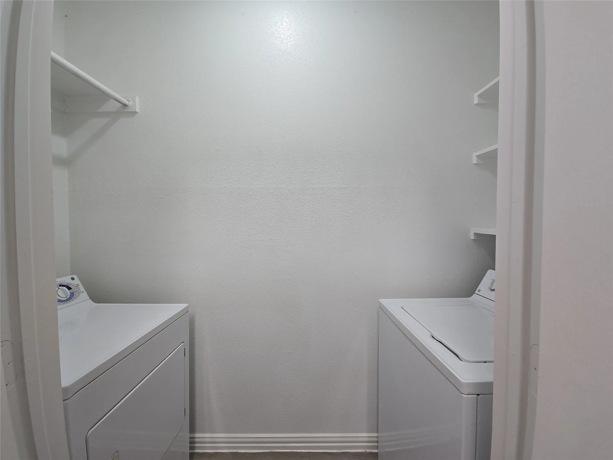 Laundry area featuring white walls, a built-in shelving unit, and a clothes rod