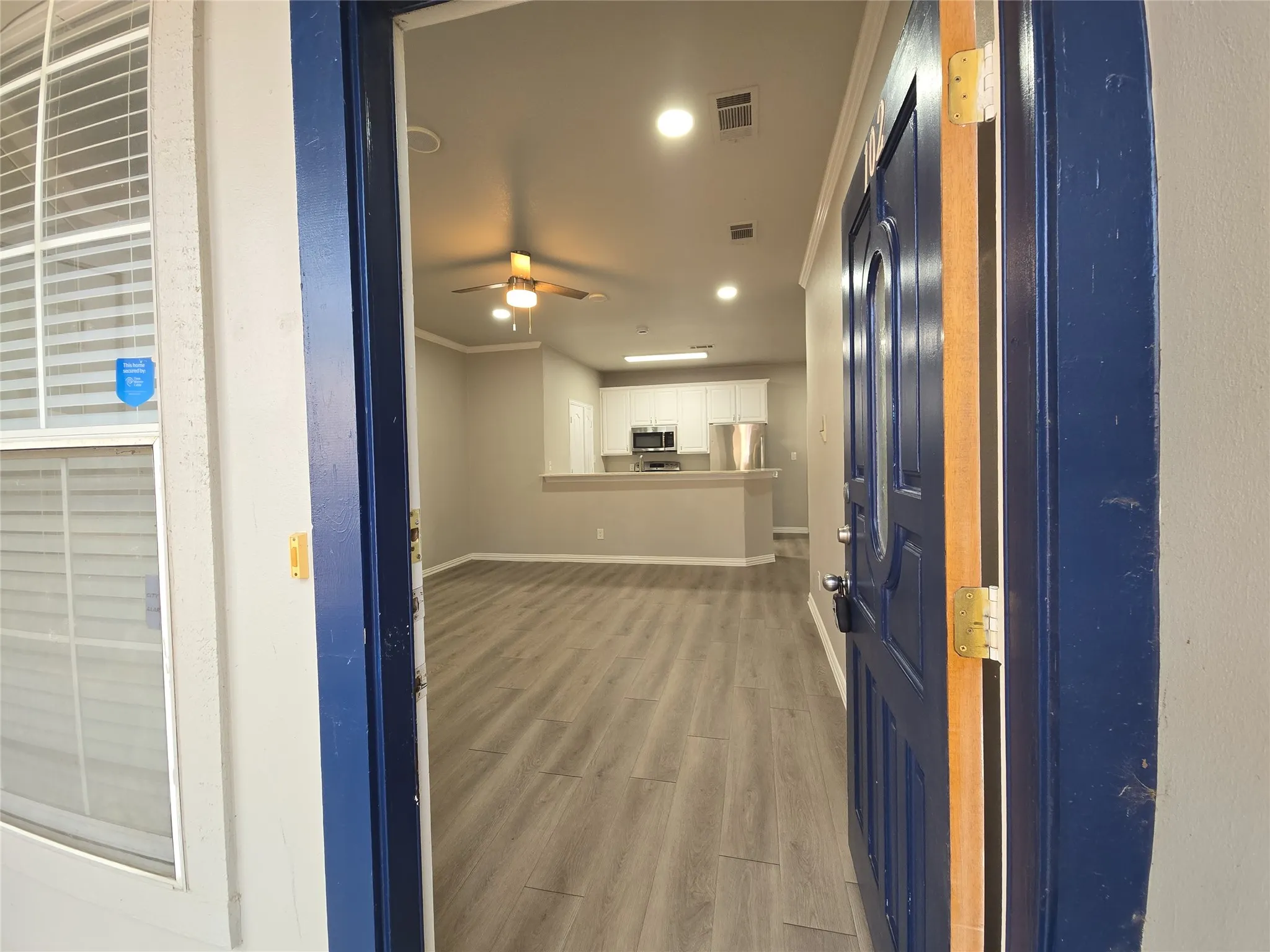 Entryway opening to an open-concept living area with wood-finish flooring, recessed lighting, and a ceiling fan