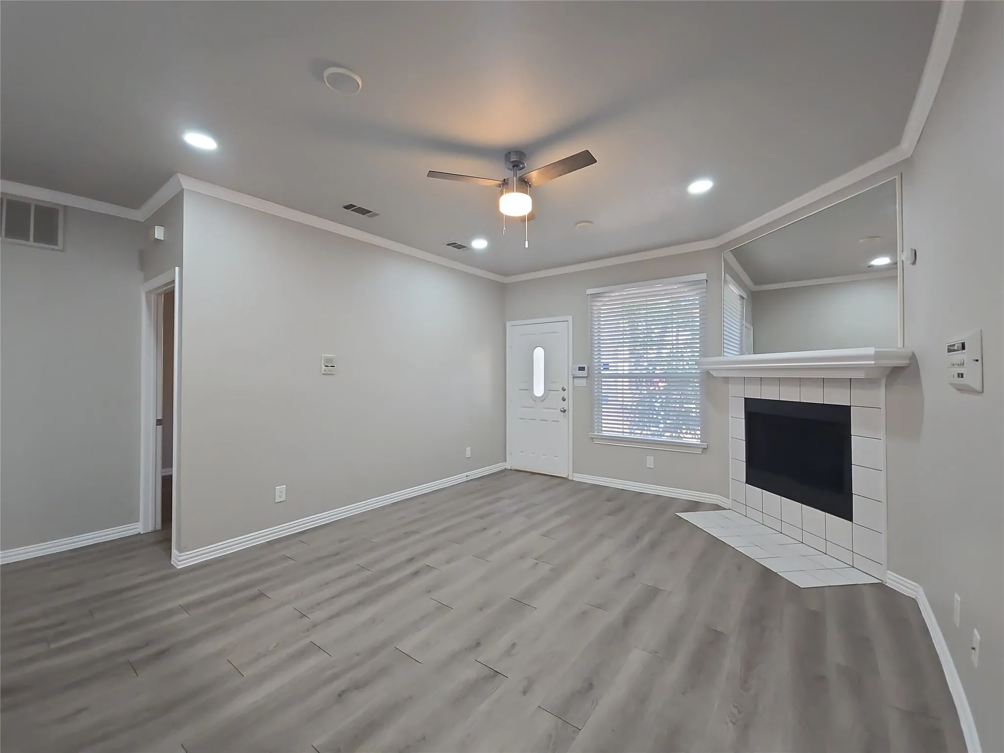 Light wood-finish flooring, recessed lighting, and a ceiling fan create an inviting atmosphere