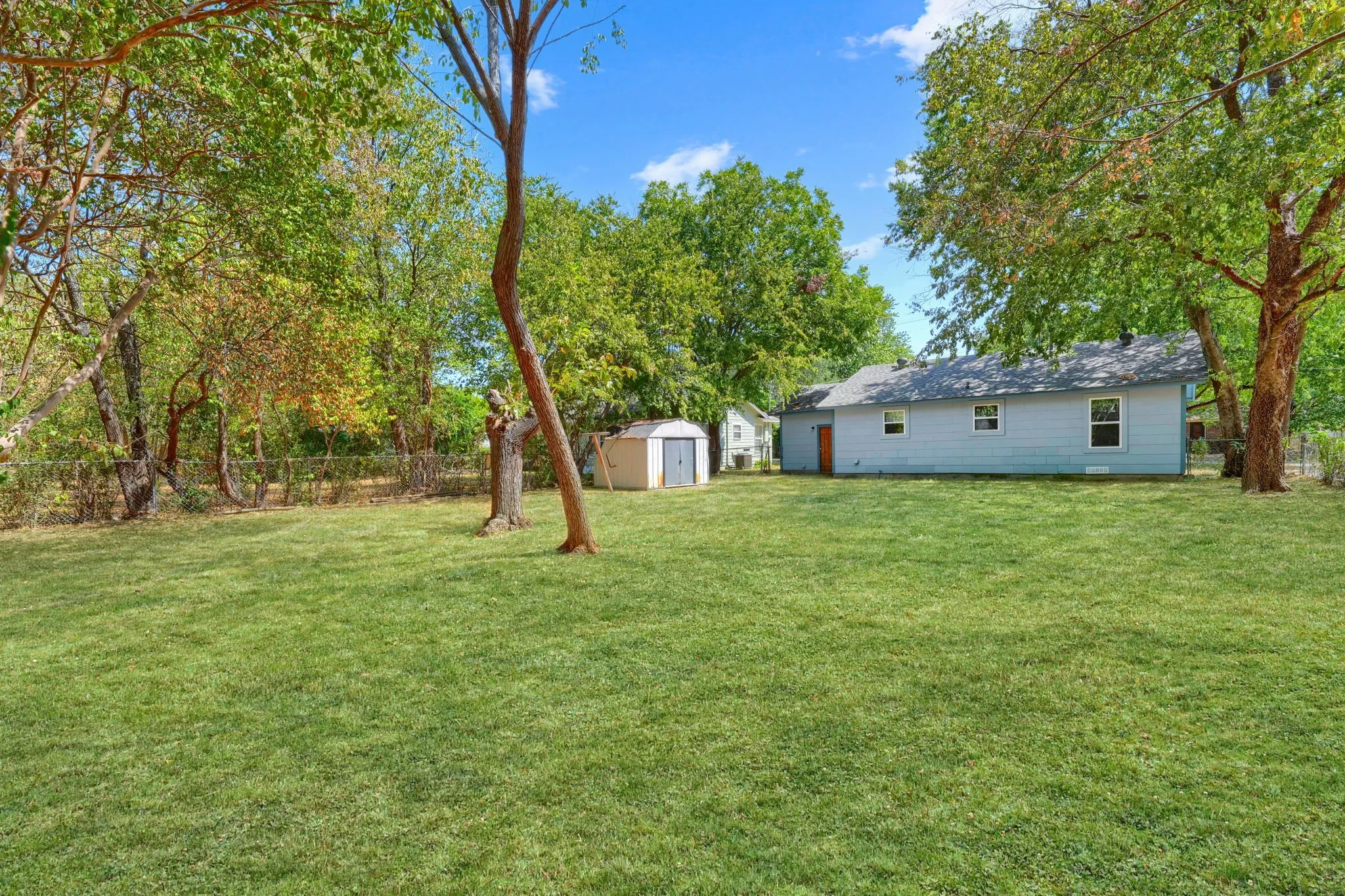 Expansive lawn area, mature trees, and a detached storage shed