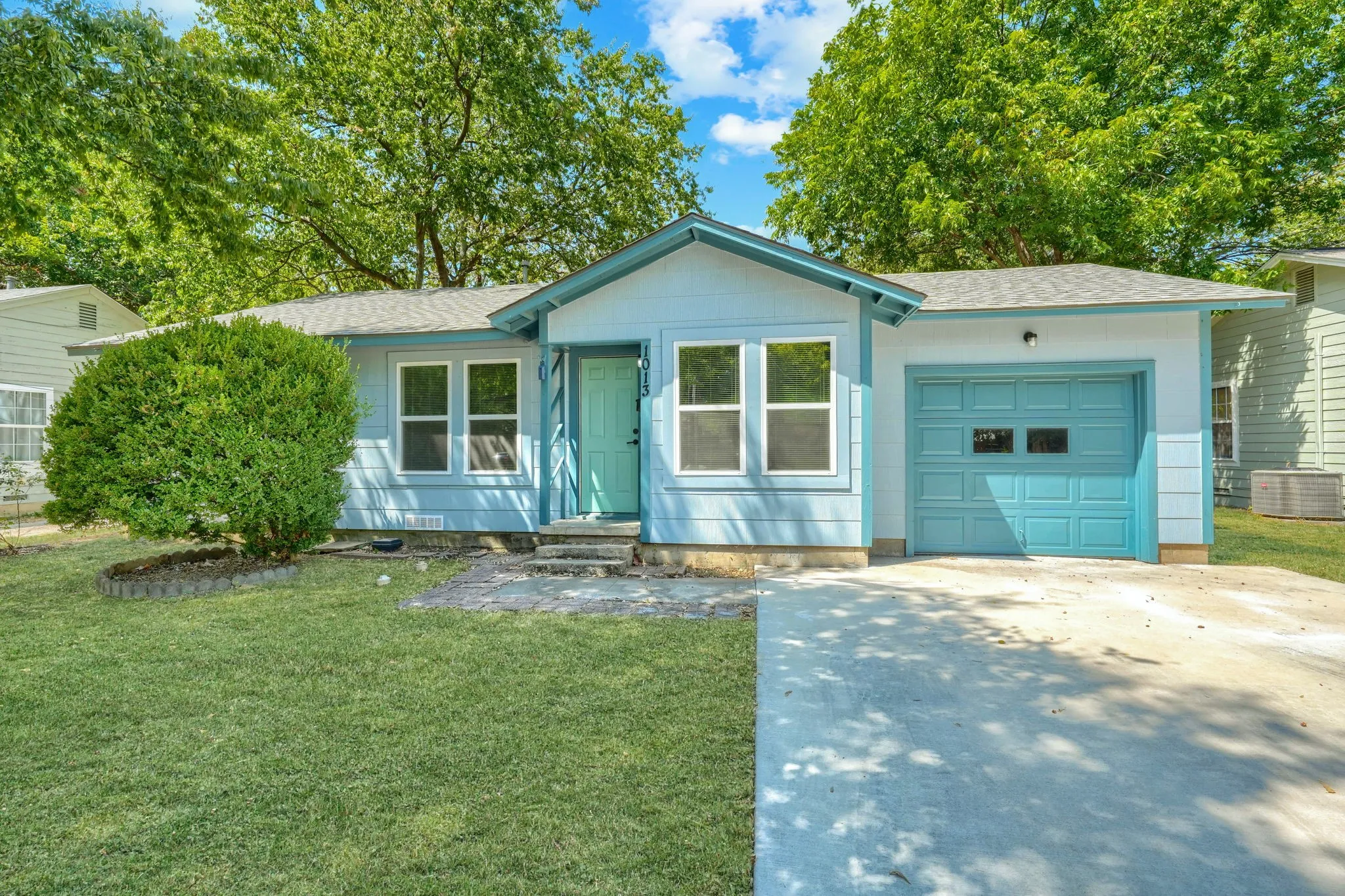 Light blue siding exterior with a bright teal front door and garage door