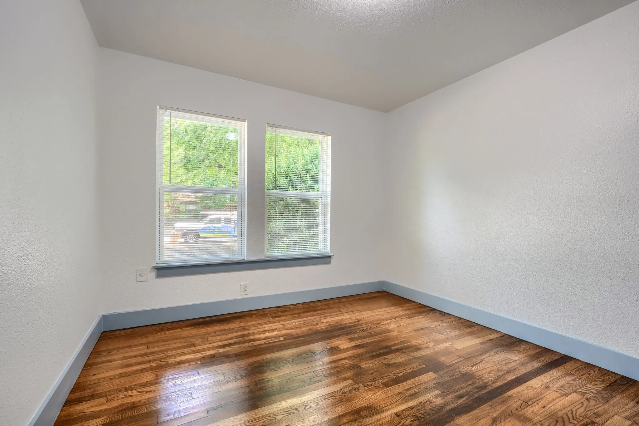 Hardwood flooring, dual windows, neutral wall tones, and recessed lighting