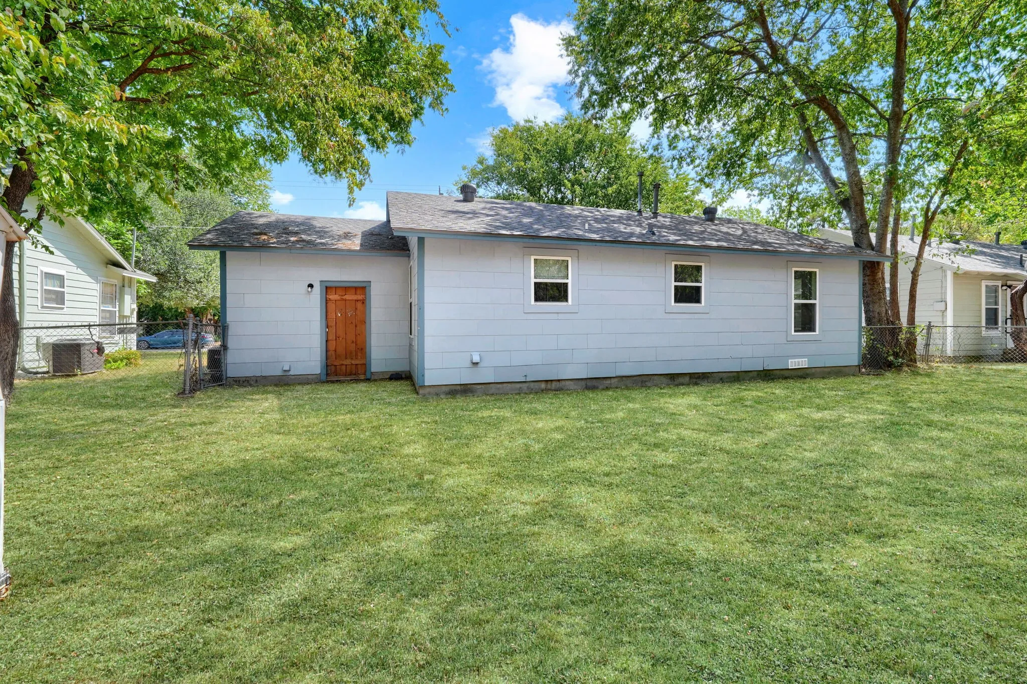 Expansive green lawn with mature trees and a fenced perimeter
