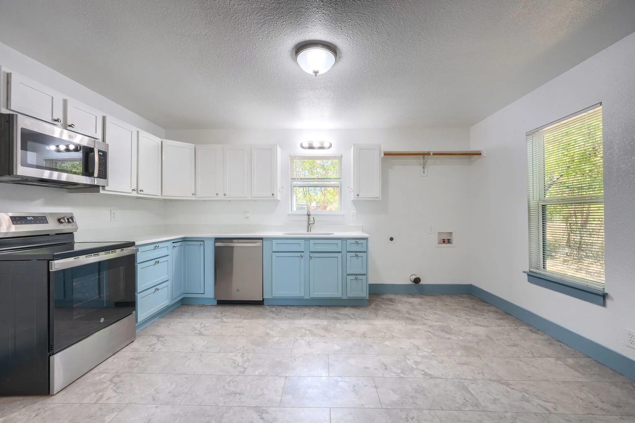 Corner kitchen with two-tone cabinetry, stainless steel appliances, and a dedicated laundry area