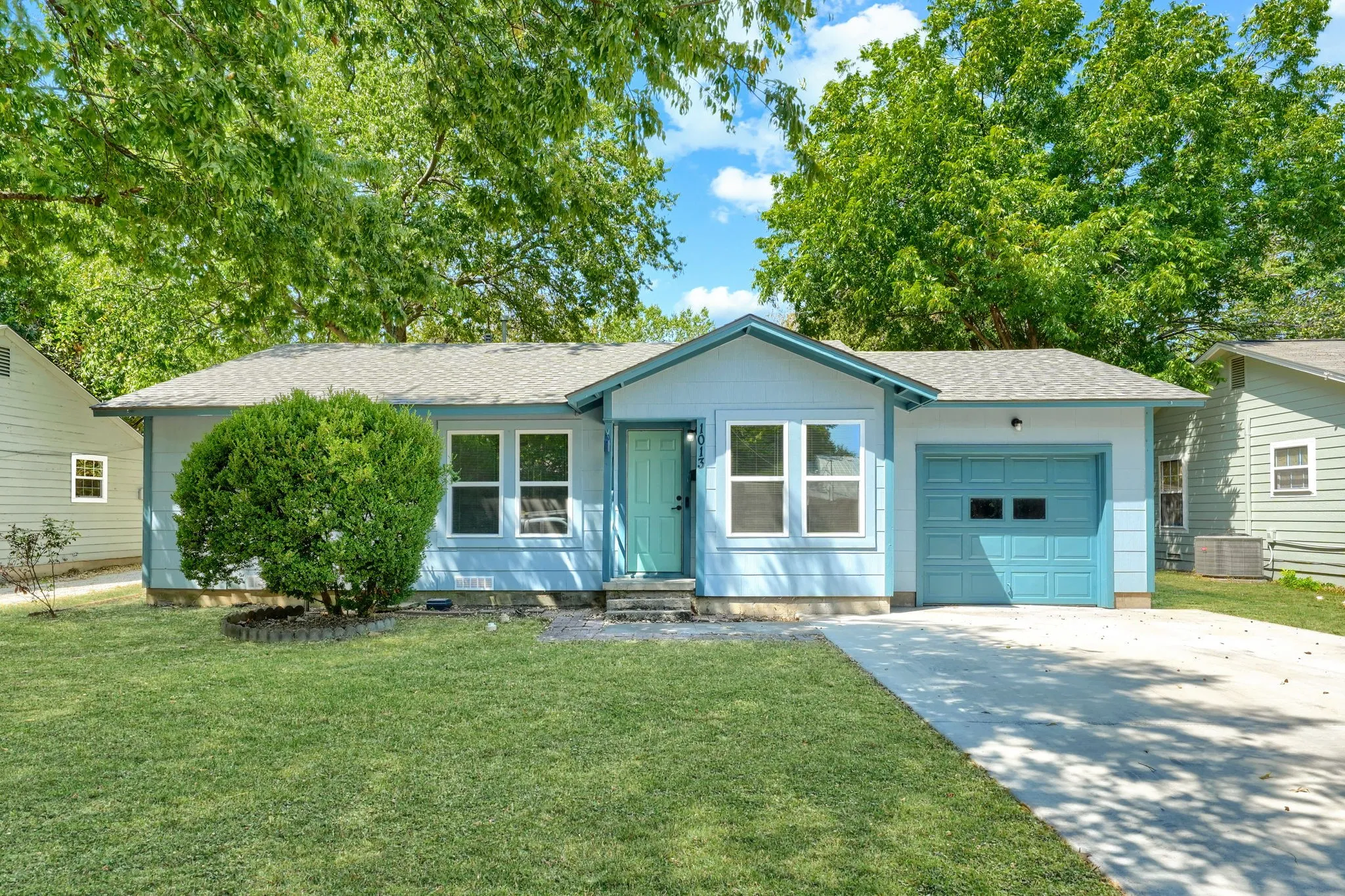 Light blue exterior with white trim, a teal front door, and a matching teal garage door