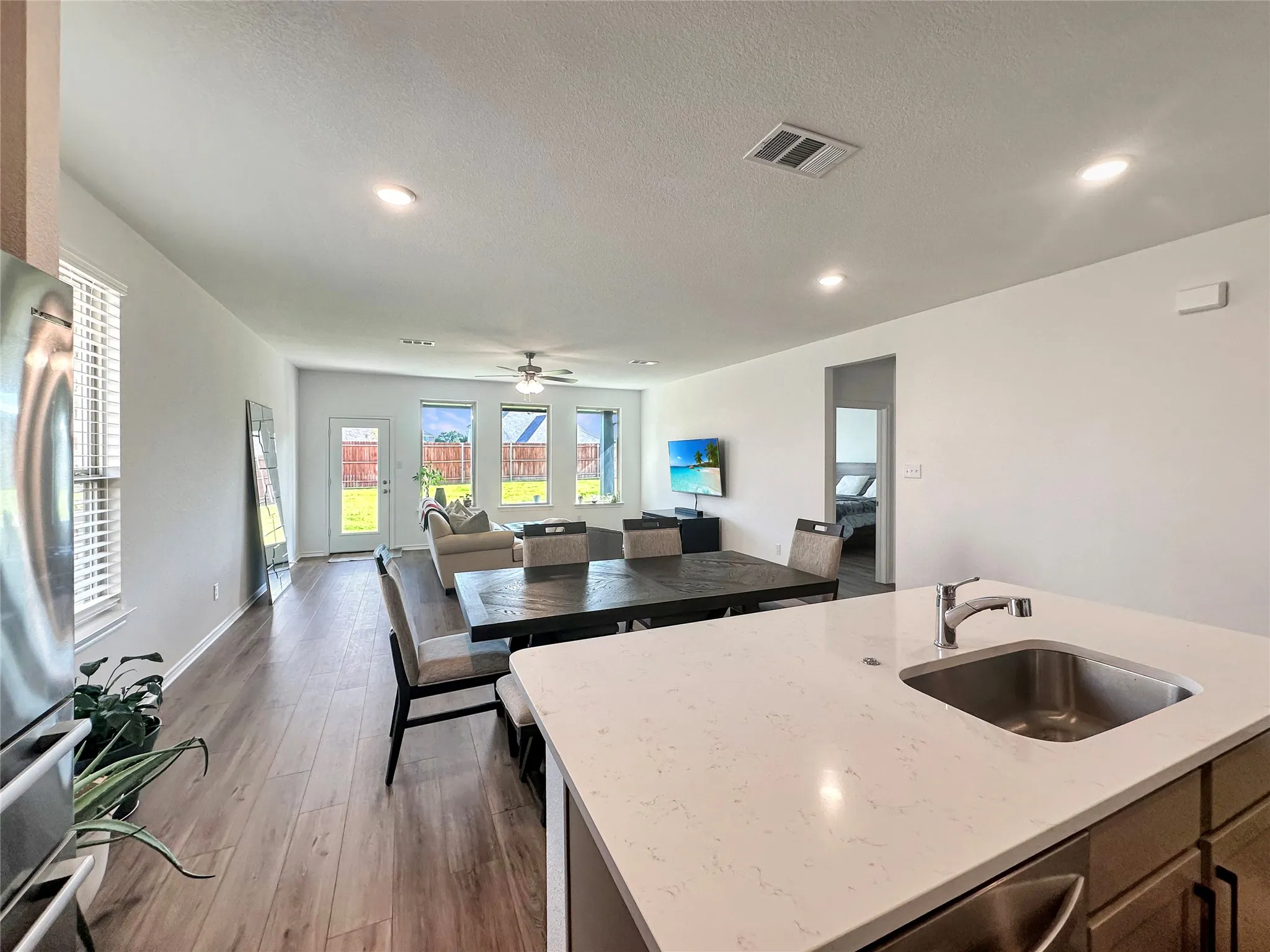Kitchen featuring light stone countertops, dark hardwood / wood-style flooring, a center island with sink, sink, and ceiling fan