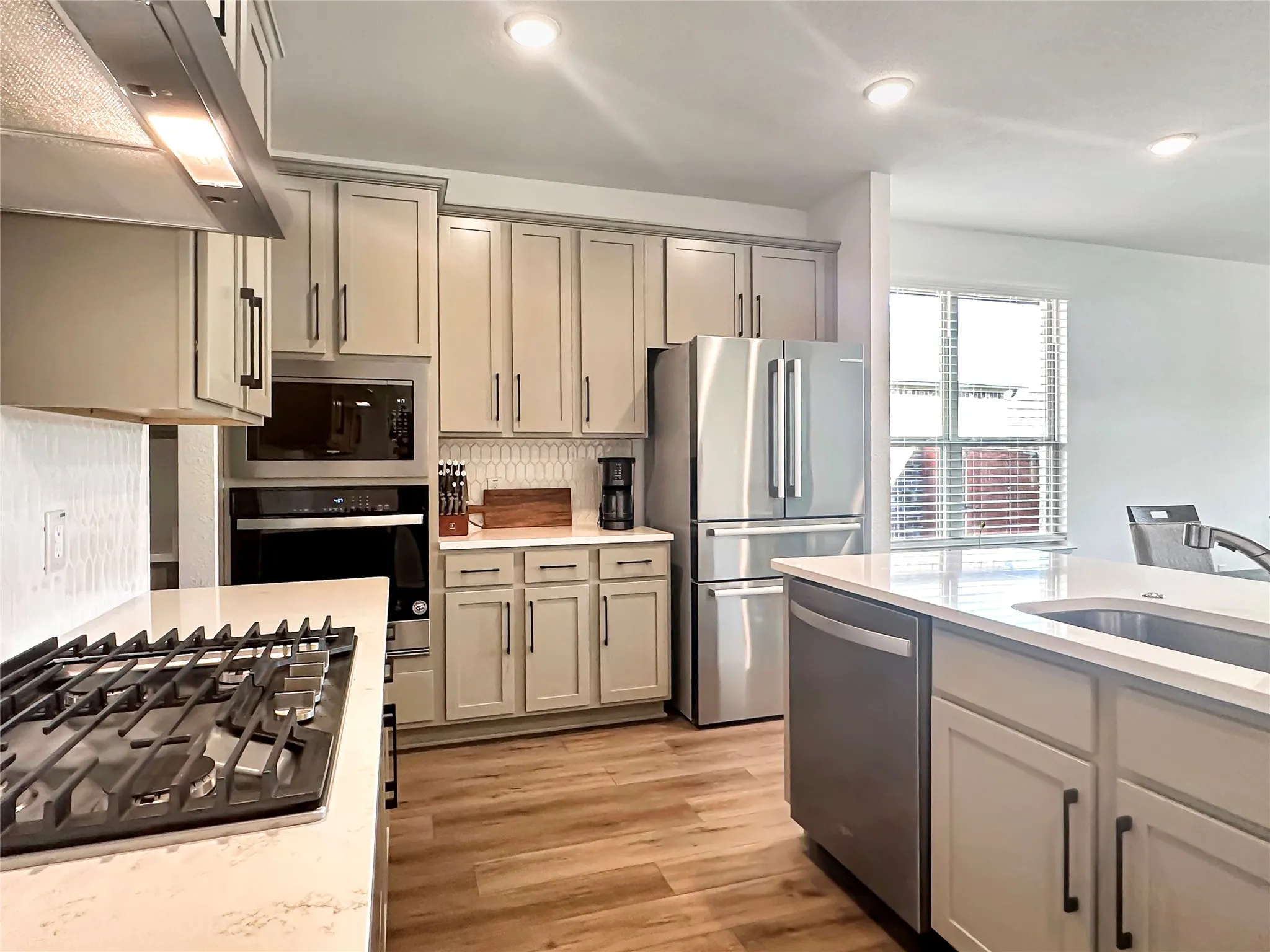 Kitchen with ventilation hood, light hardwood / wood-style flooring, stainless steel appliances, and gray cabinetry