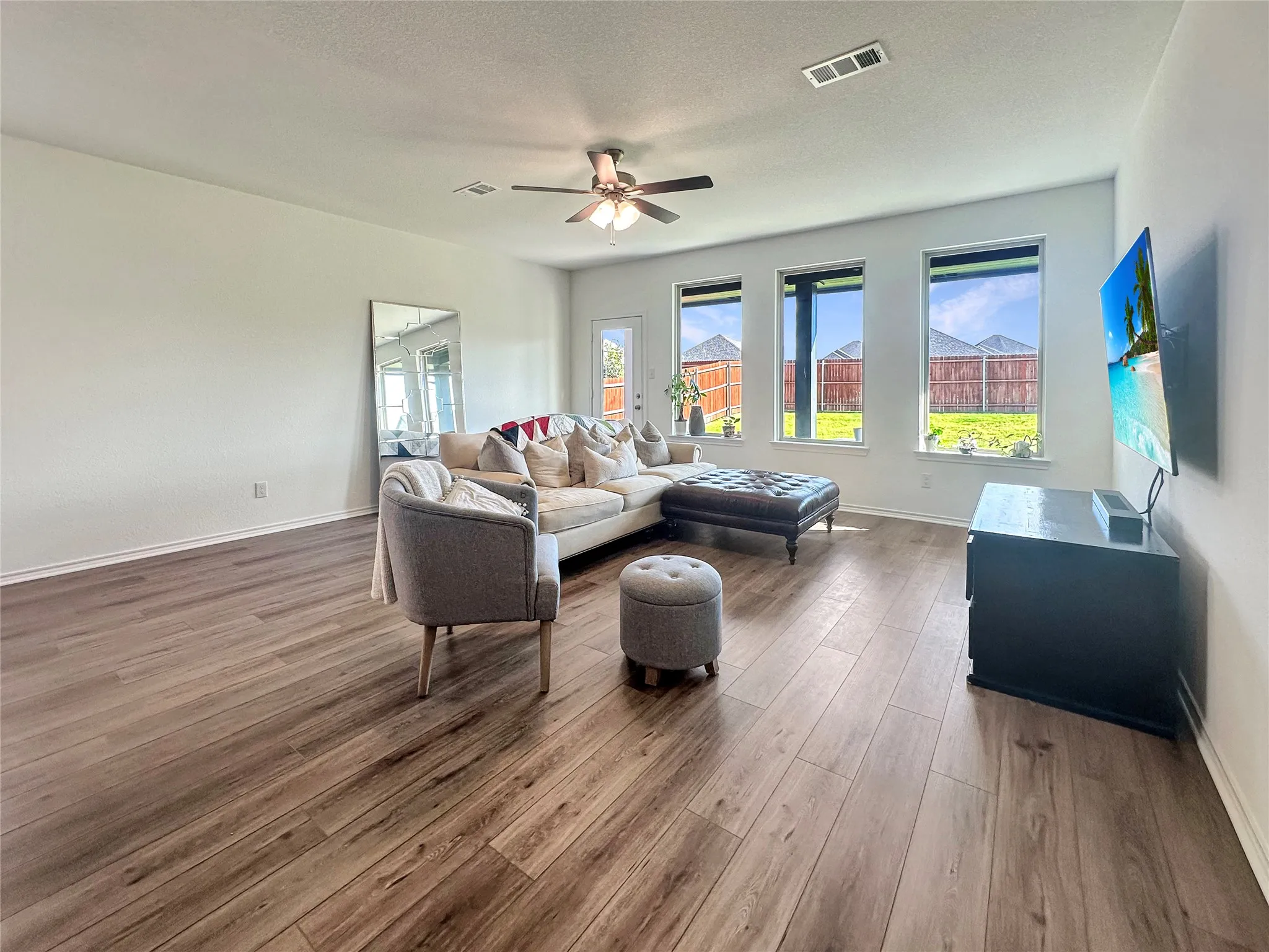 Living room featuring dark wood-type flooring, a textured ceiling, and ceiling fan